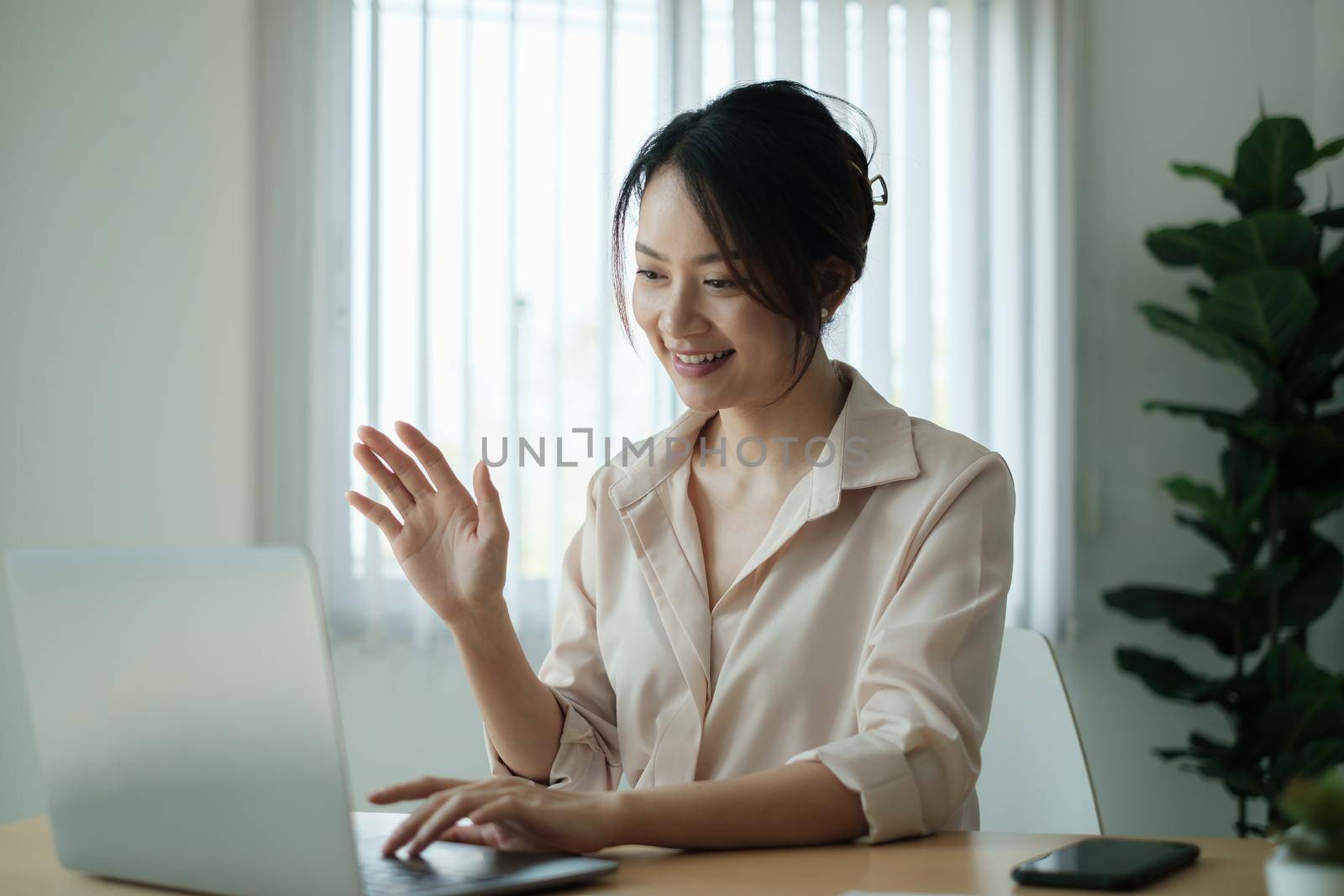 Asian Business woman sitting in office with laptop computer on wooden desk. by itchaznong