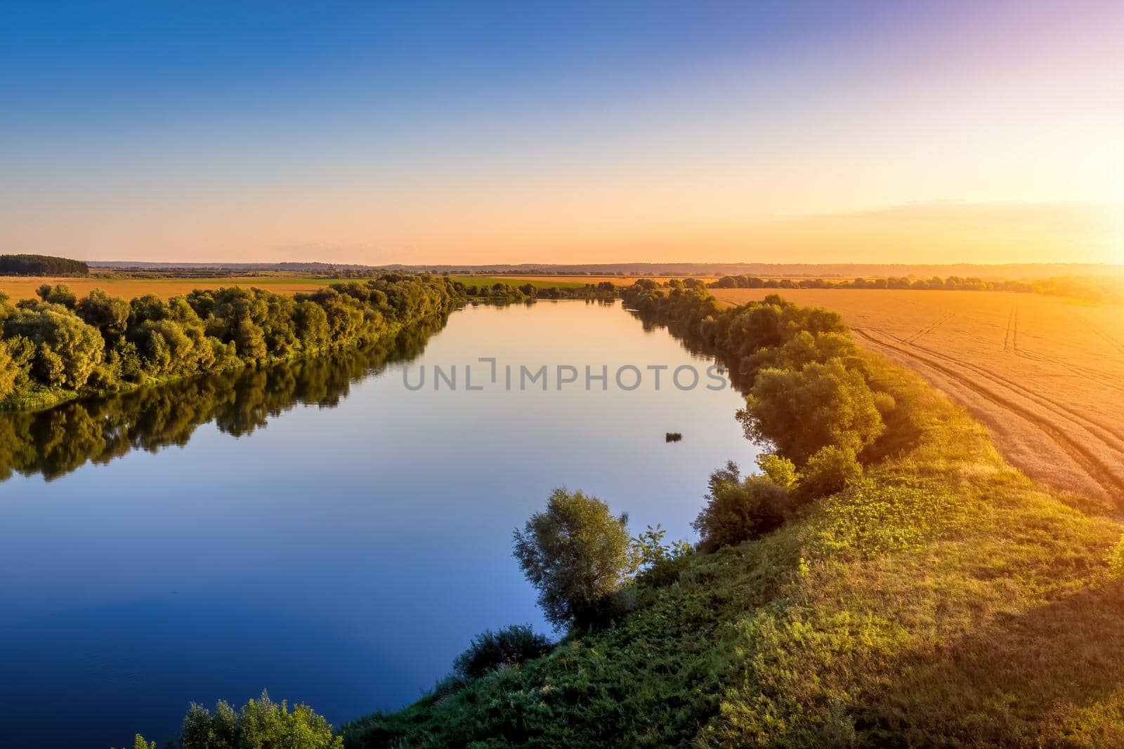 A sunset or sunrise scene over a lake or river with skies reflecting in the water on a summer evening or morning. Landscape.