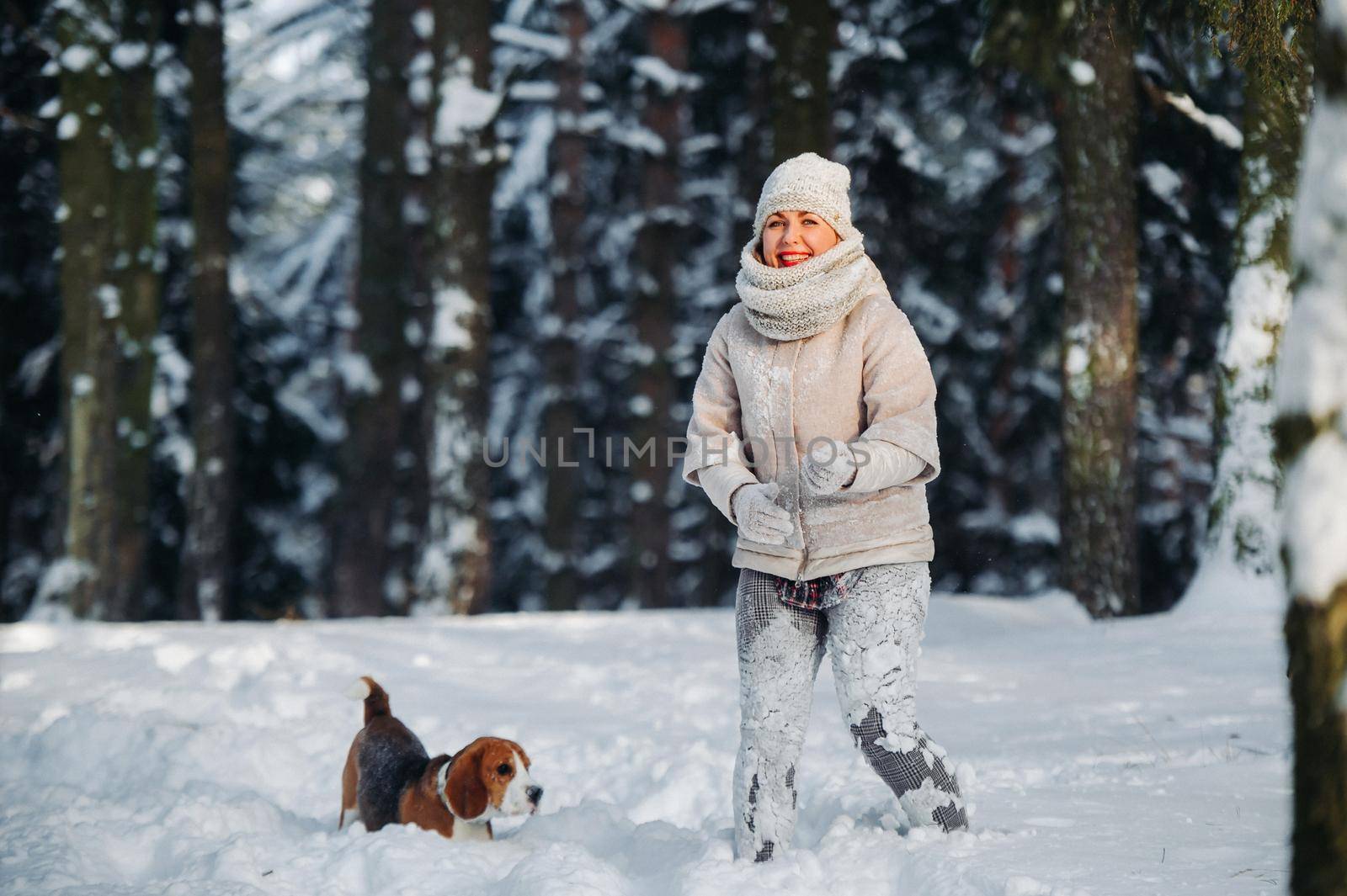 a woman on a walk with her dog in the winter forest. mistress and dog game in the snowy forest.