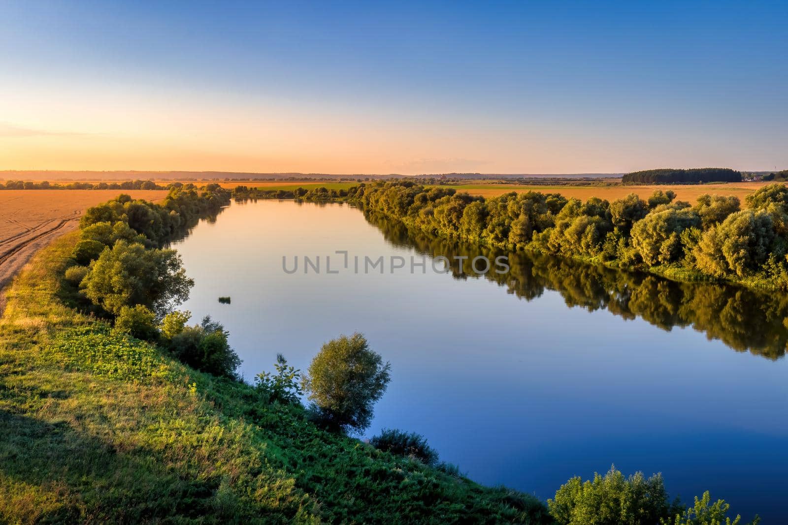 A sunset or sunrise scene over a lake or river with skies reflecting in the water on a summer evening or morning. Landscape.