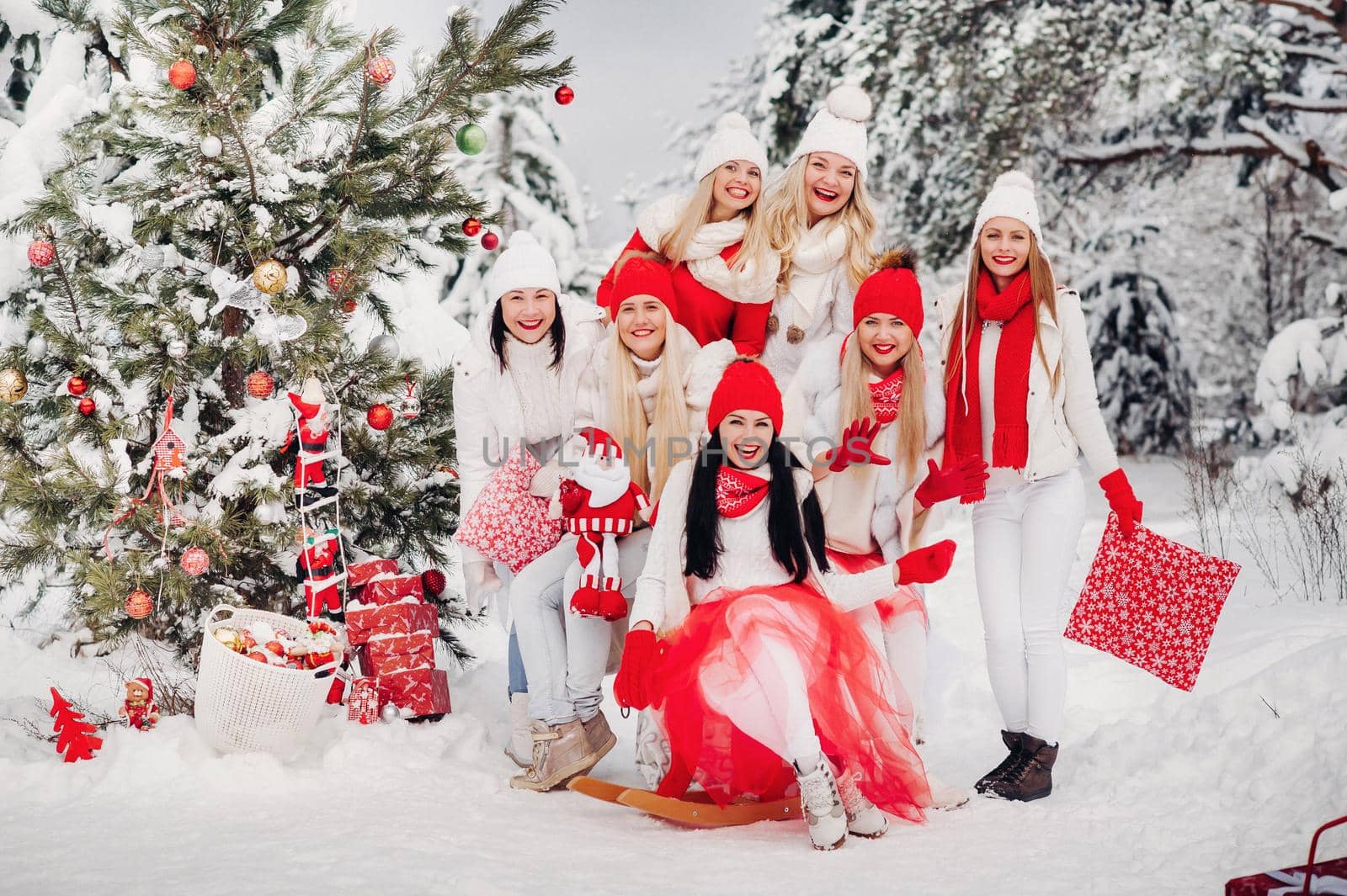 A large group of girls with Christmas gifts in their hands standing in the winter forest.Girls in red and white clothes with Christmas gifts in the snowy forest.