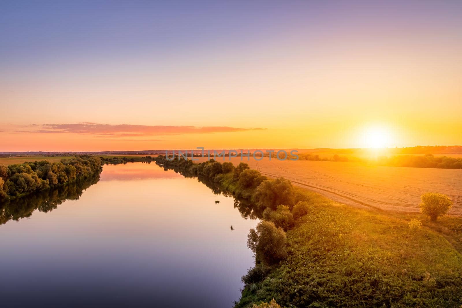 A sunset or sunrise scene over a lake or river with skies reflecting in the water on a summer evening or morning. Landscape.