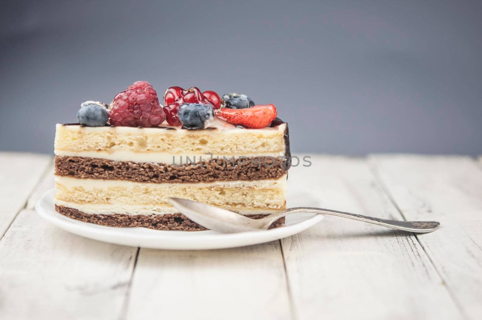 Mix berry slice cake on white plate on wood background