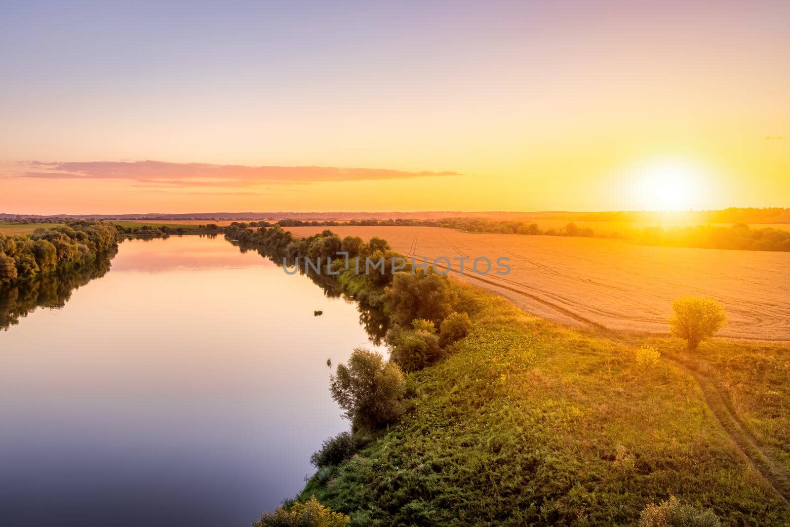 A sunset or sunrise scene over a lake or river with skies reflecting in the water on a summer evening or morning. Landscape.