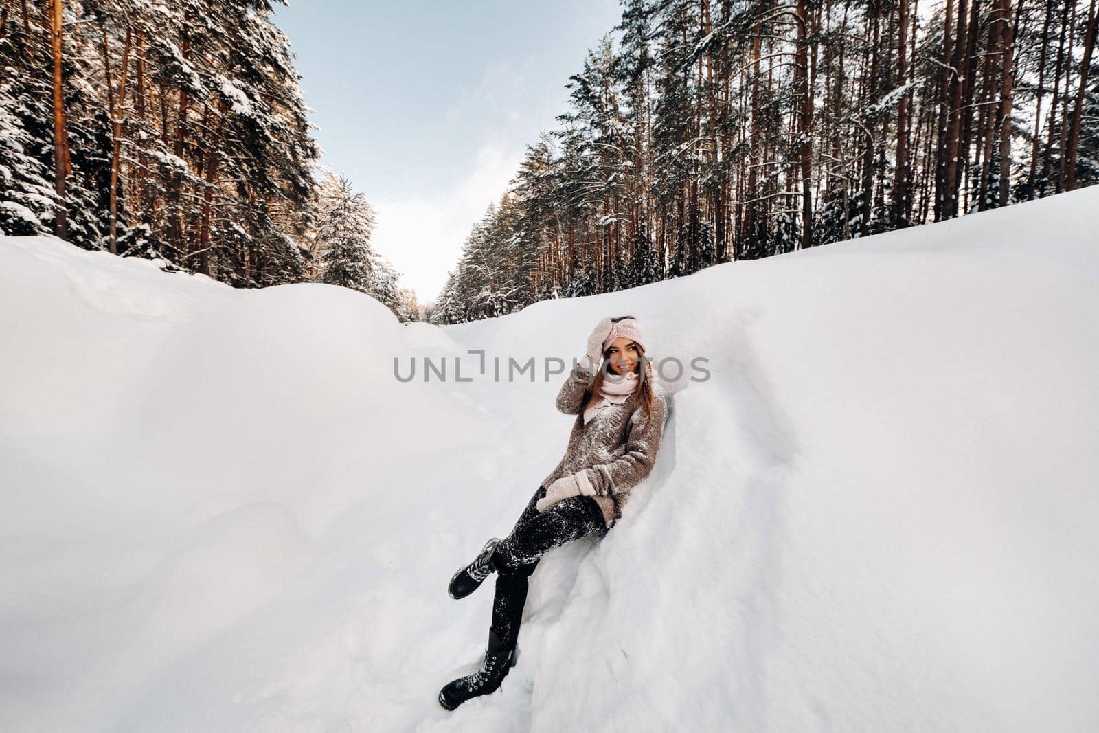 A girl in a sweater and mittens in winter stands on a snow-covered background.