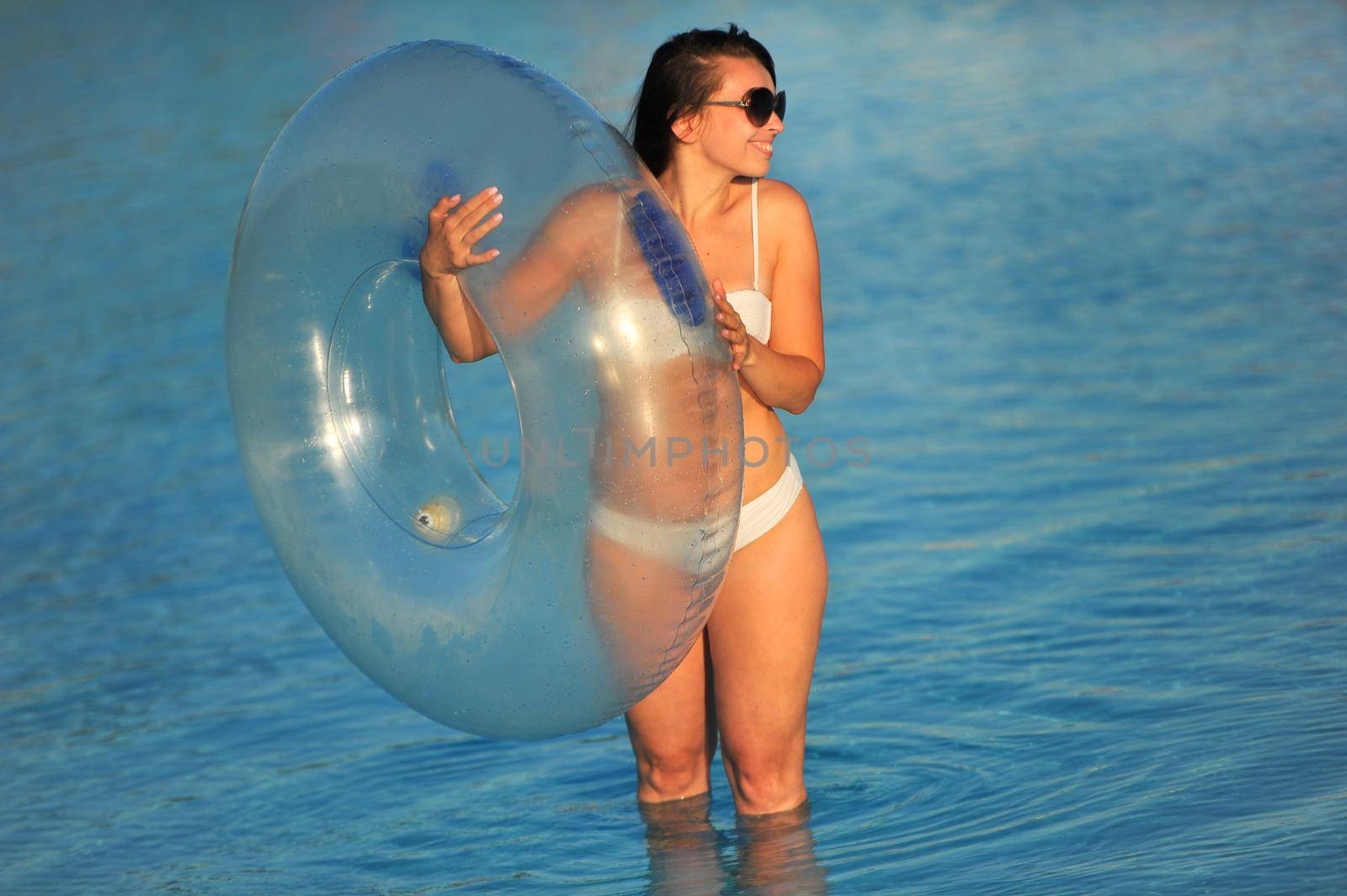 A woman in a white bathing suit with an inflatable circle in a water Park.