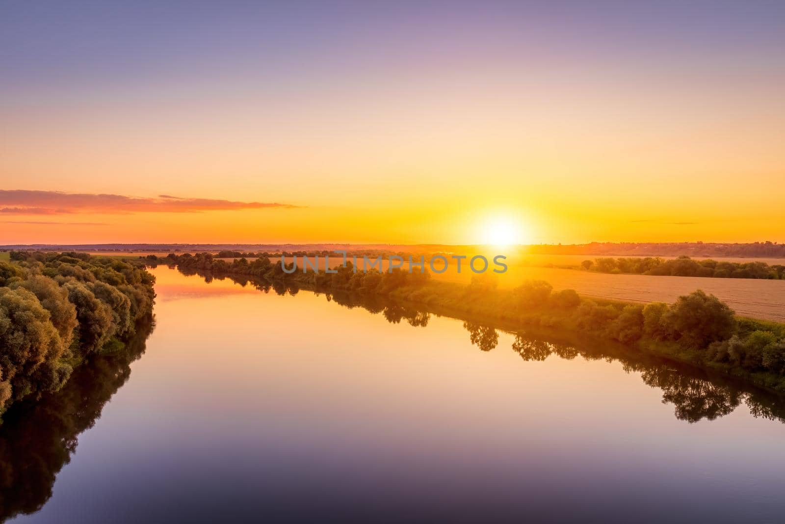 A sunset or sunrise scene over a lake or river with skies reflecting in the water on a summer evening or morning. Landscape.