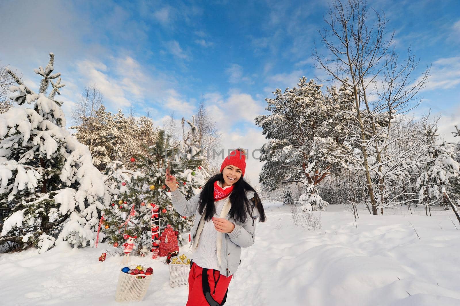 Happy girl in the winter forest takes a selfie near the Christmas tree. A woman smiles in a snow-covered forest on Christmas day.