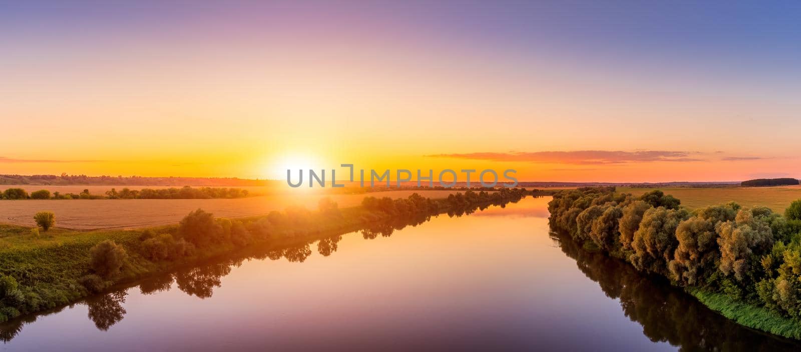 A sunset or sunrise scene over a lake or river with skies reflecting in the water on a summer evening or morning. Landscape.