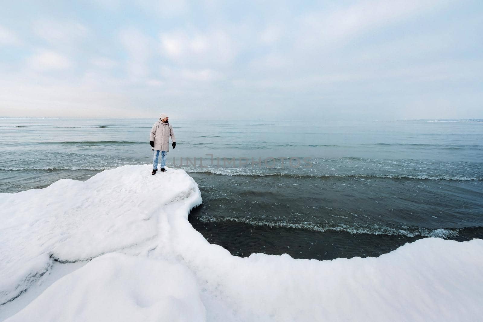 A tourist stands on the shore of the Baltic sea in winter. Winter near the Baltic States of Tallinn.Traveler near the sea in winter