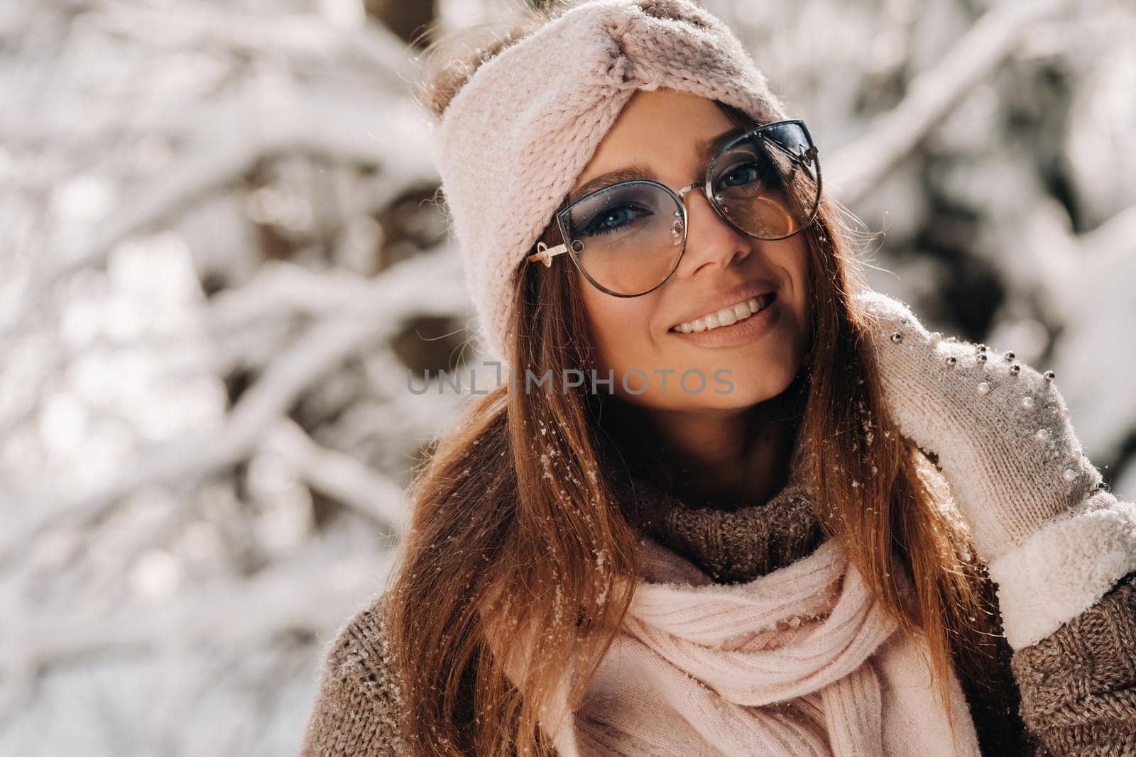 A girl in a sweater and glasses in winter in a snow-covered forest by Lobachad