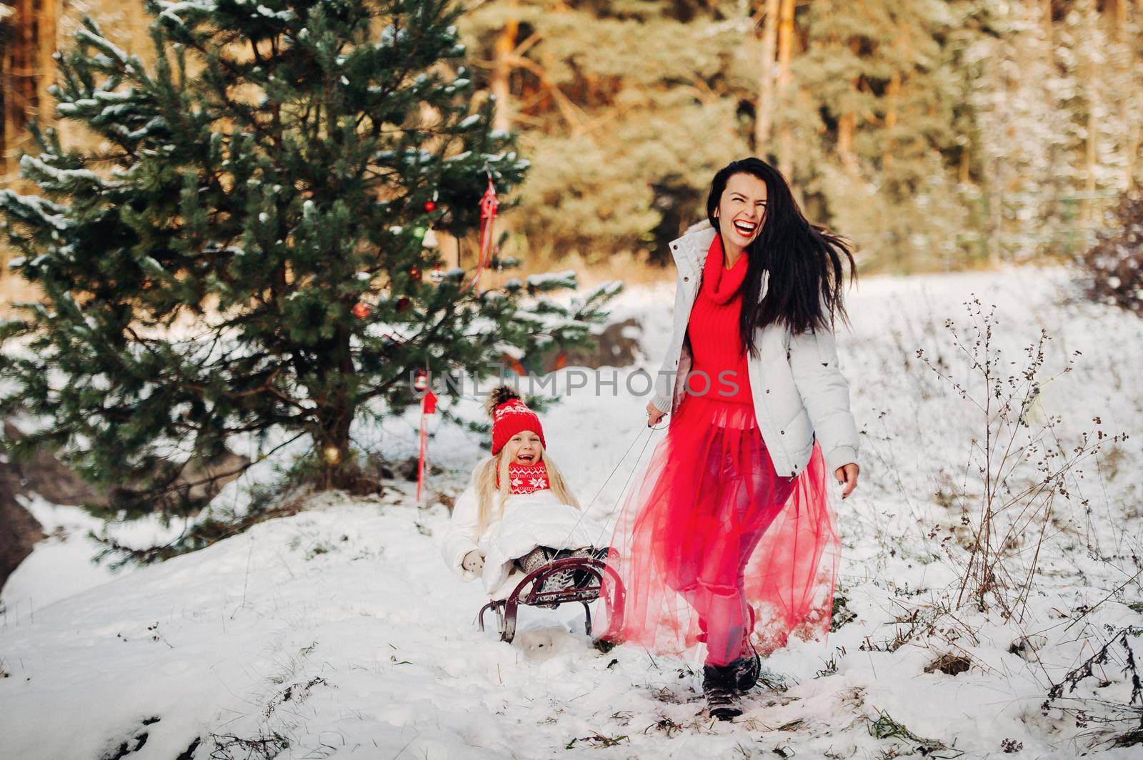 Emotional girl sledding a little girl in a snowy forest.Winter mood by Lobachad