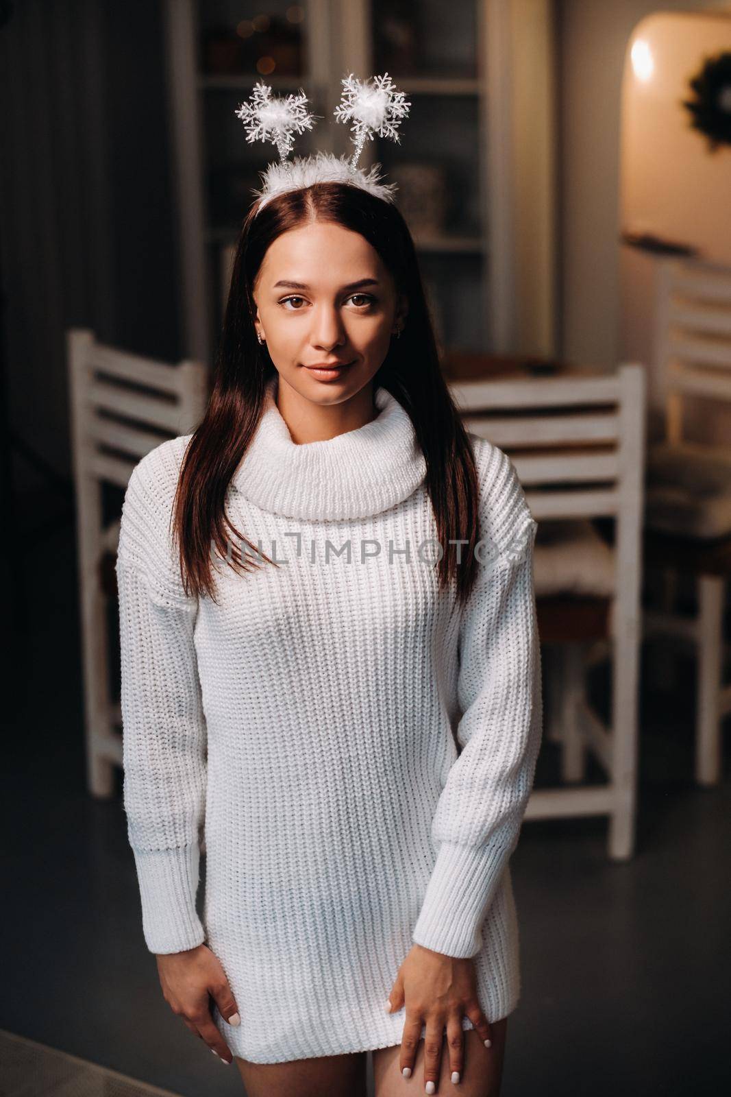 Girl at Christmas with horns in the home interior.A woman on New year's eve in a white sweater.