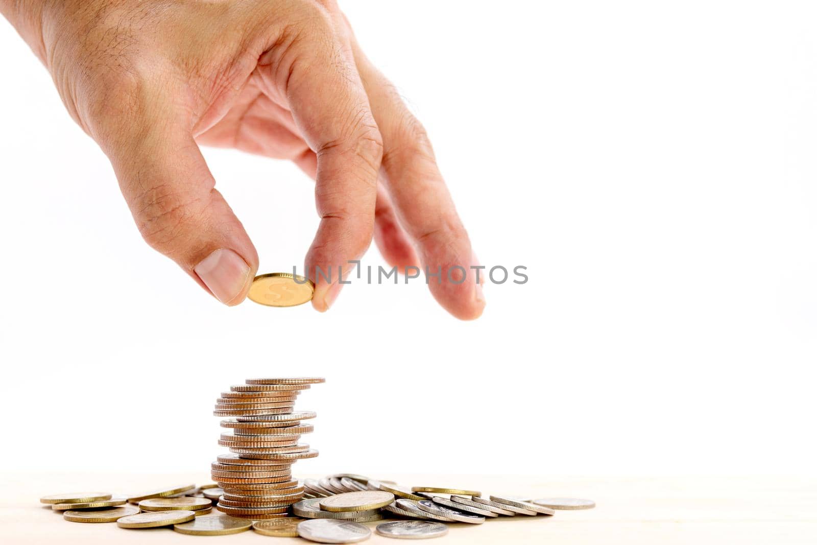 Closeup of human hand putting a coin on a pile of coins, use for business and finance concepts.