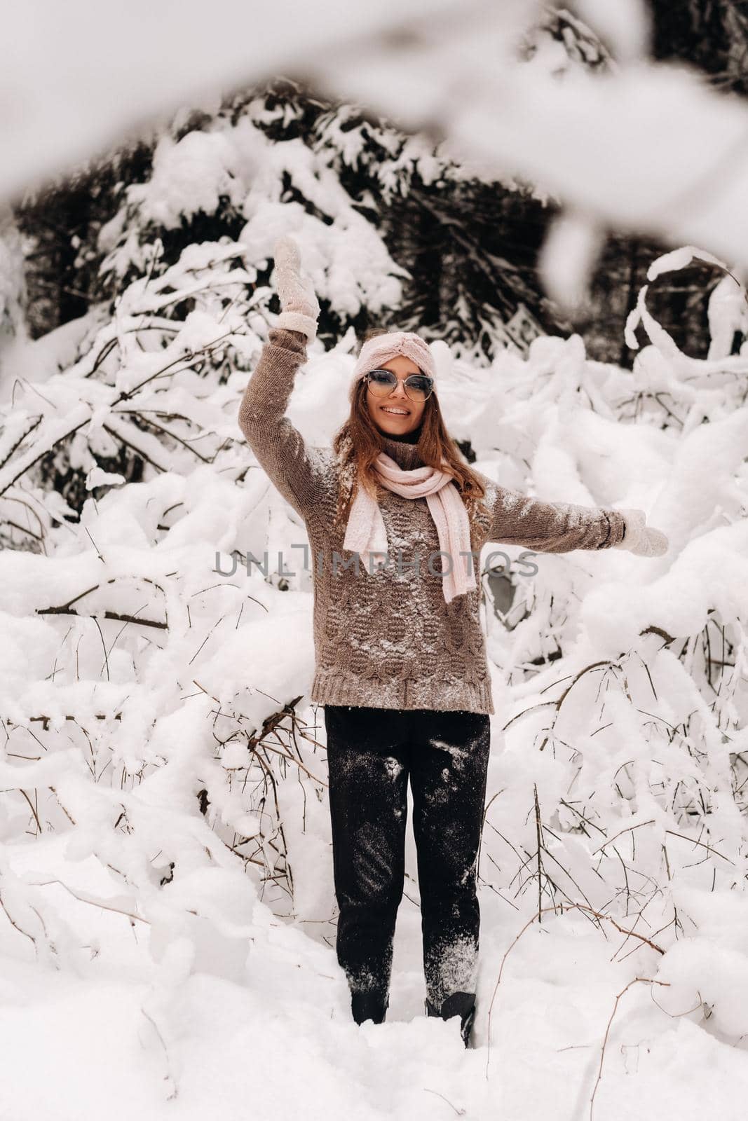 A girl in a sweater and glasses in winter in a snow-covered forest.