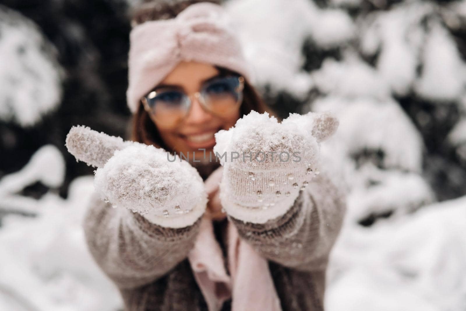 A girl in a sweater and glasses in winter in a snow-covered forest.