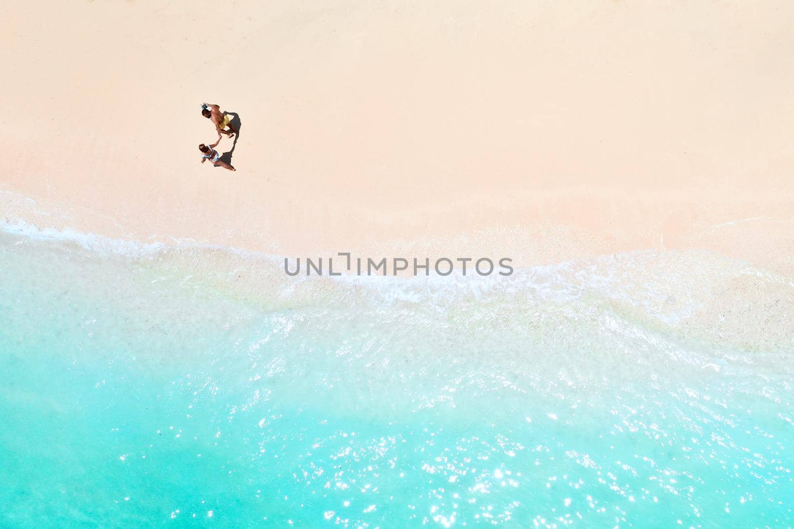 A couple walks along the Beach of Mauritius in the Indian ocean. Top view of the beach with turquoise water on the tropical island of Mauritius.Aerial photography