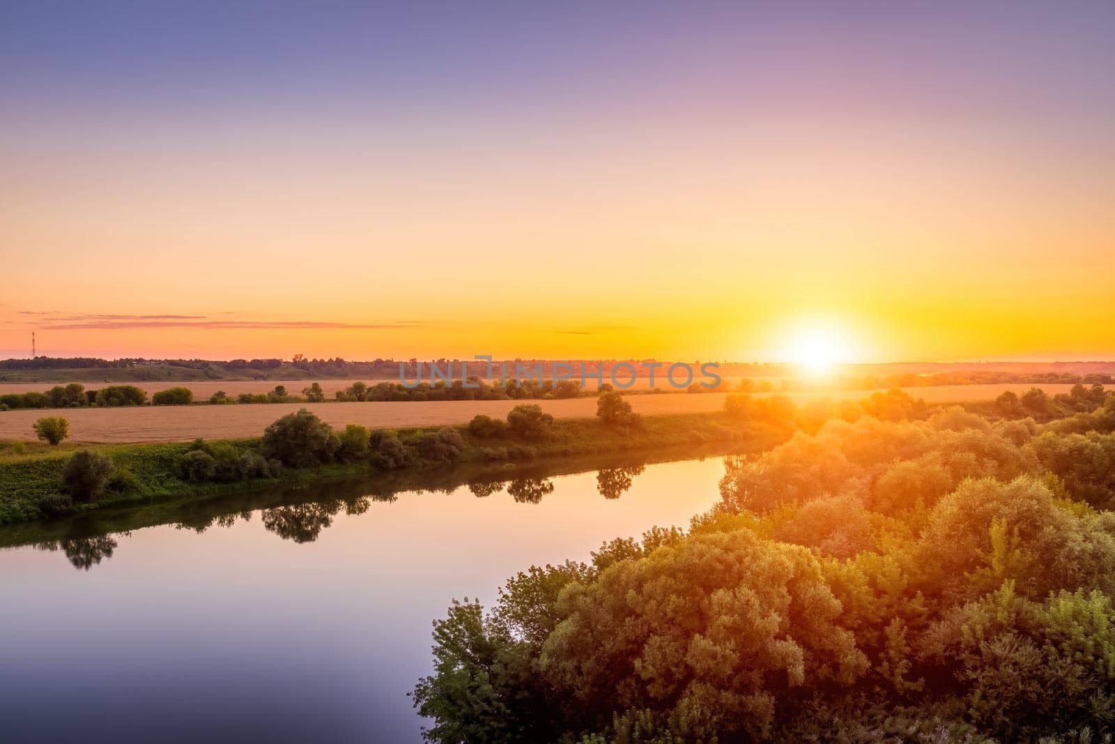 A sunset or sunrise scene over a lake or river with skies reflecting in the water on a summer evening or morning. Landscape.