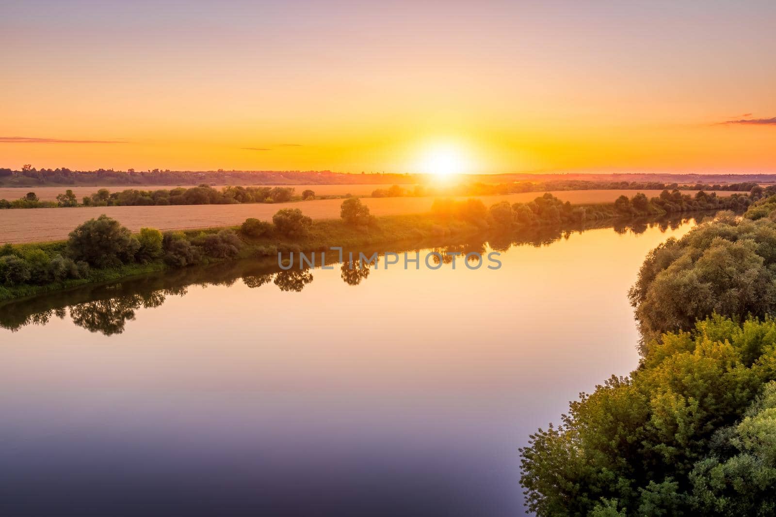 A sunset or sunrise scene over a lake or river with skies reflecting in the water on a summer evening or morning. Landscape.