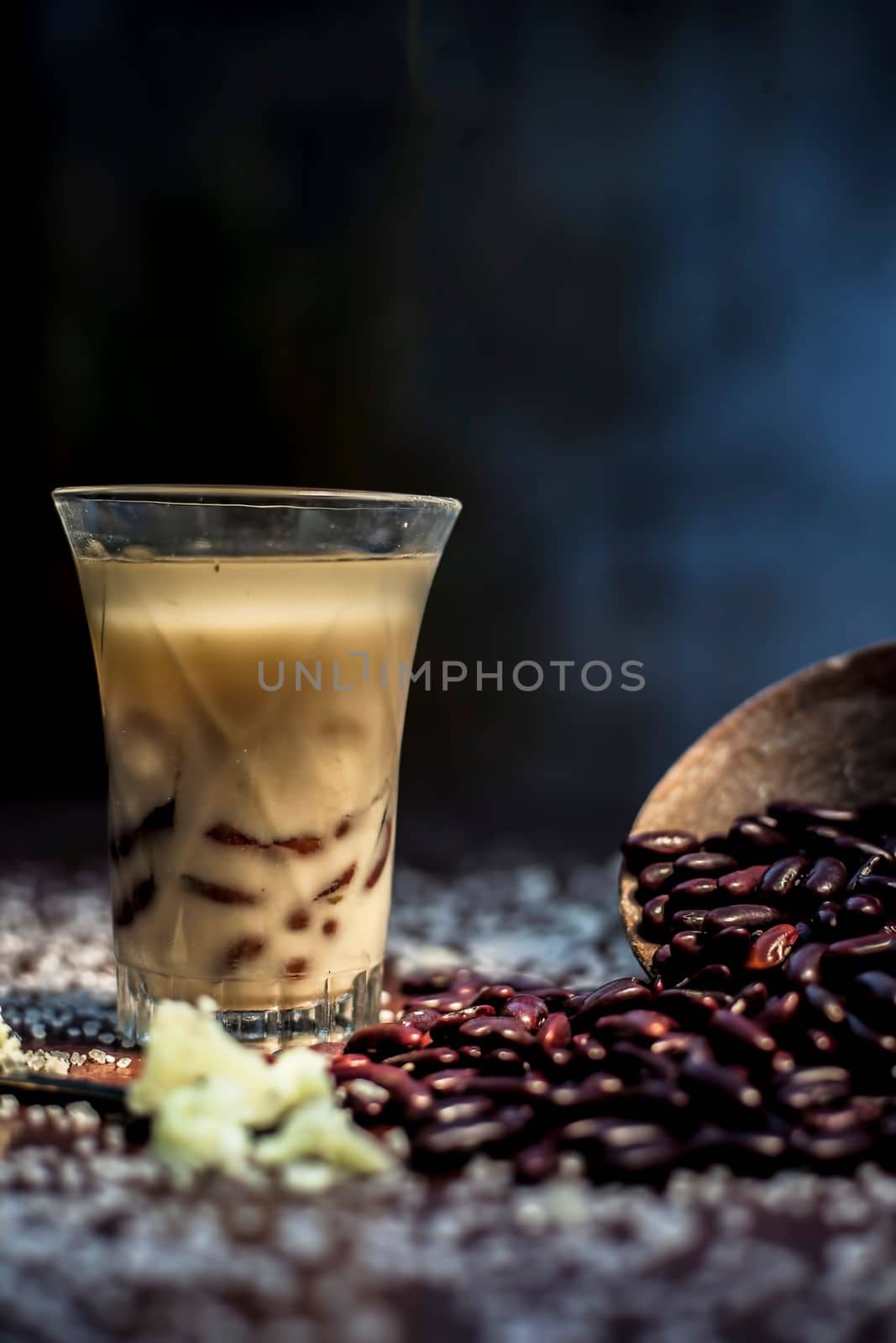 Red bean bubble tea in a glass along with some raw kidney beans, butter and sugar on the brown surface with Rembrandt light technique. Vertical shot. by mirzamlk