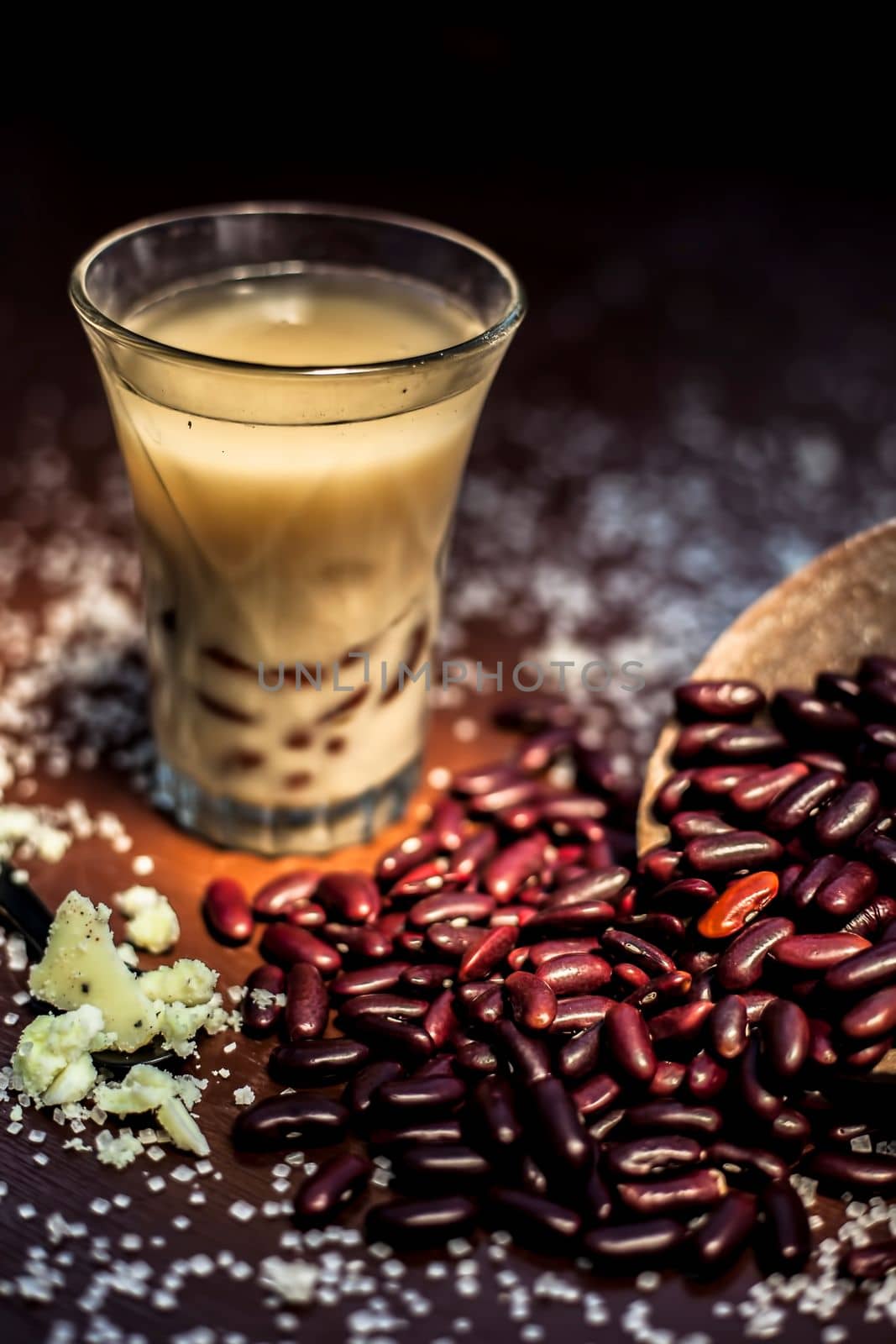 Red bean bubble tea in a glass along with some raw kidney beans, butter and sugar on the brown surface with Rembrandt light technique. Vertical shot. by mirzamlk