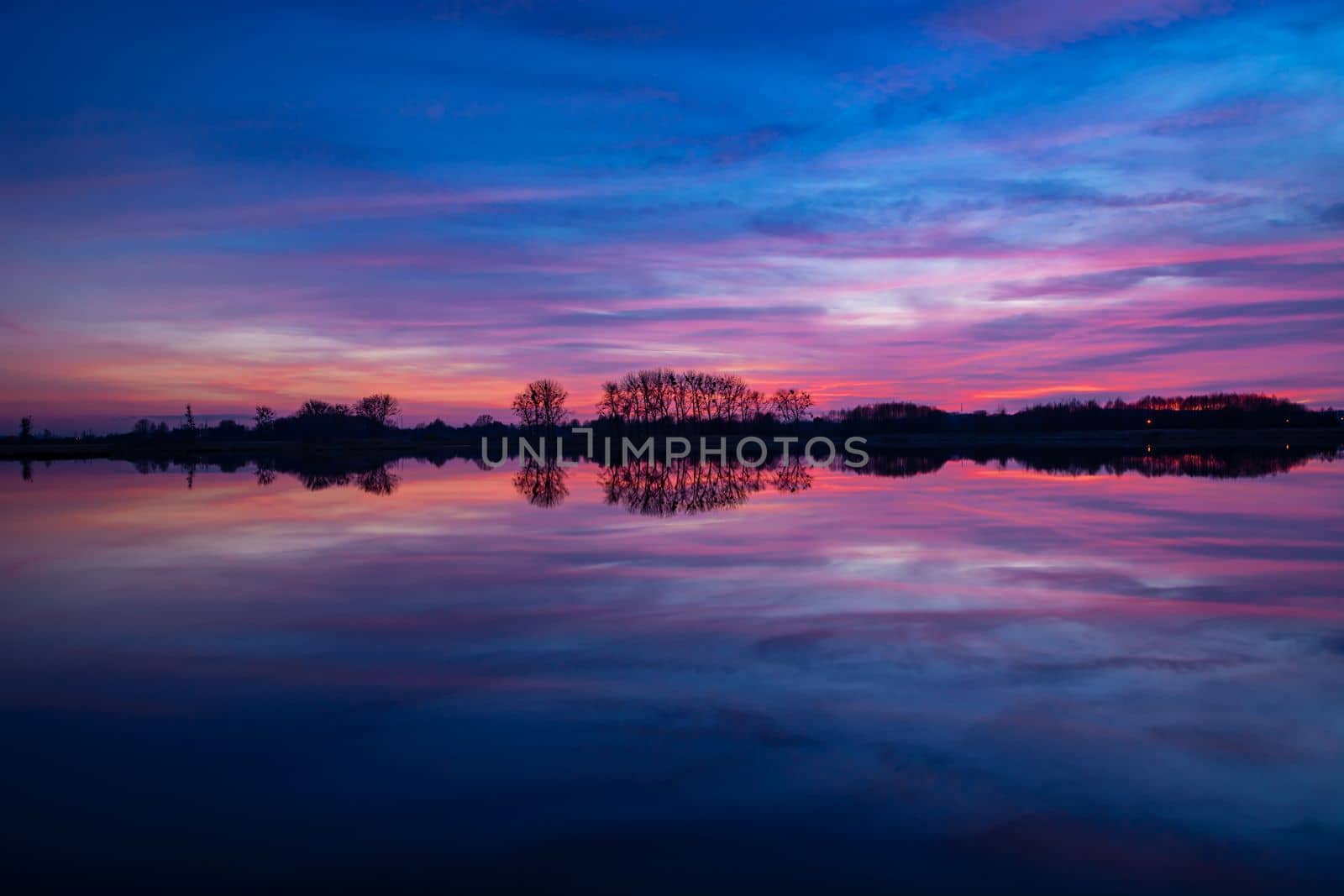 Colorful clouds after sunset and reflection in the lake water