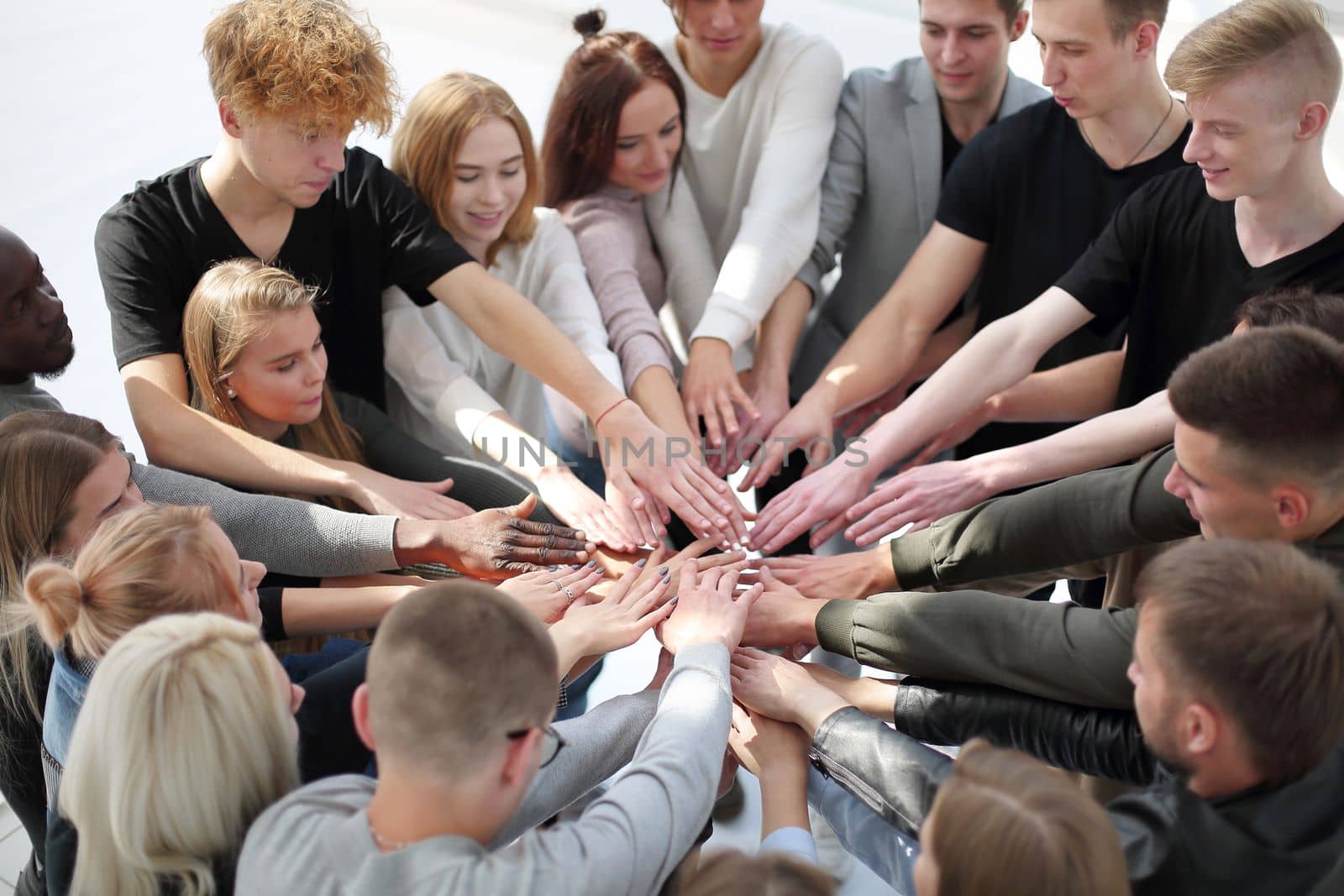 close up. a group of diverse people joining their hands in a circle.