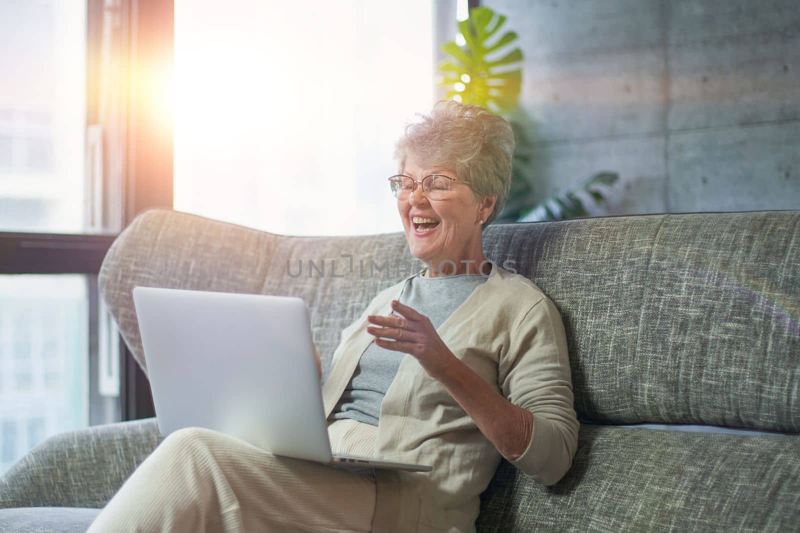 Woman using laptop while sitting on sofa in living room at home