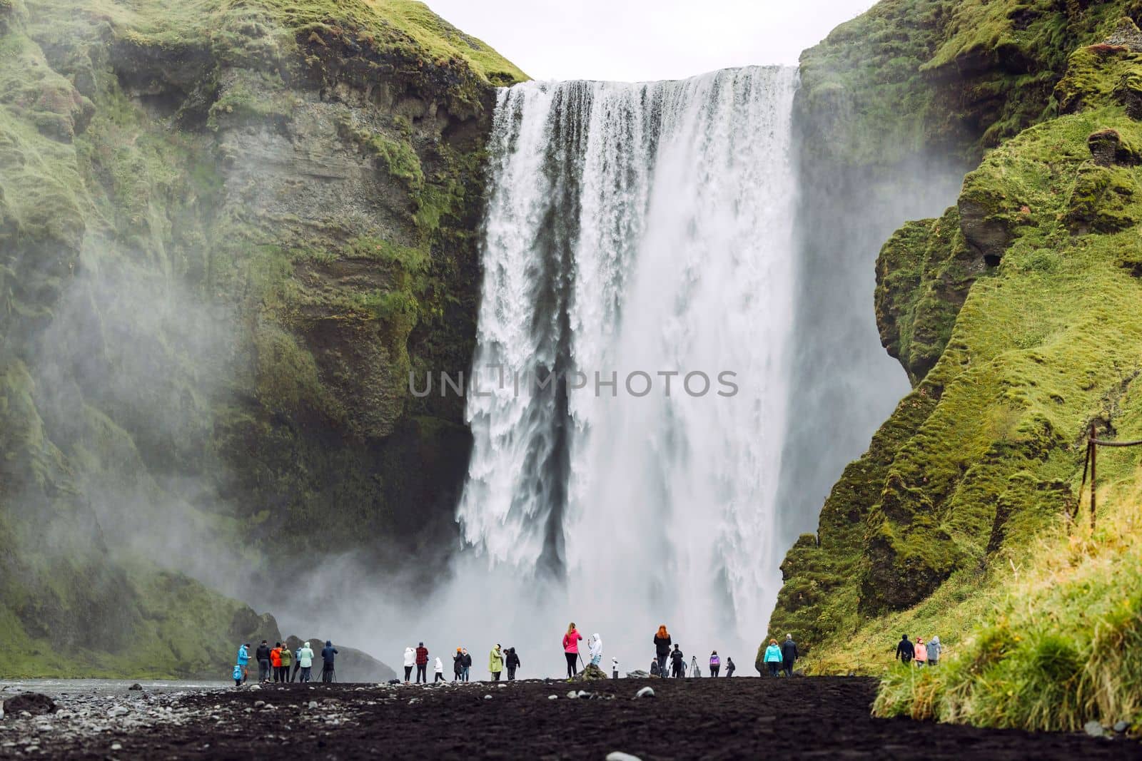 Famous Skogafoss waterfall on Skoga river.Crowds of tourist standing under the waterfall. Iceland, Europe. Landscape photography. High quality photo