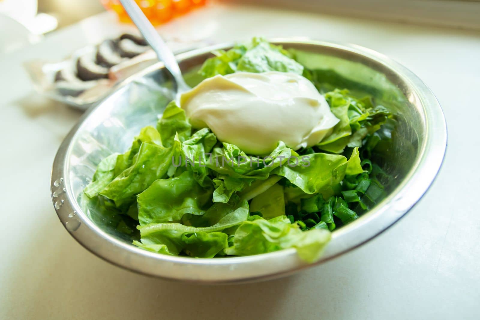 Sour cream on green lettuce in a silver bowl