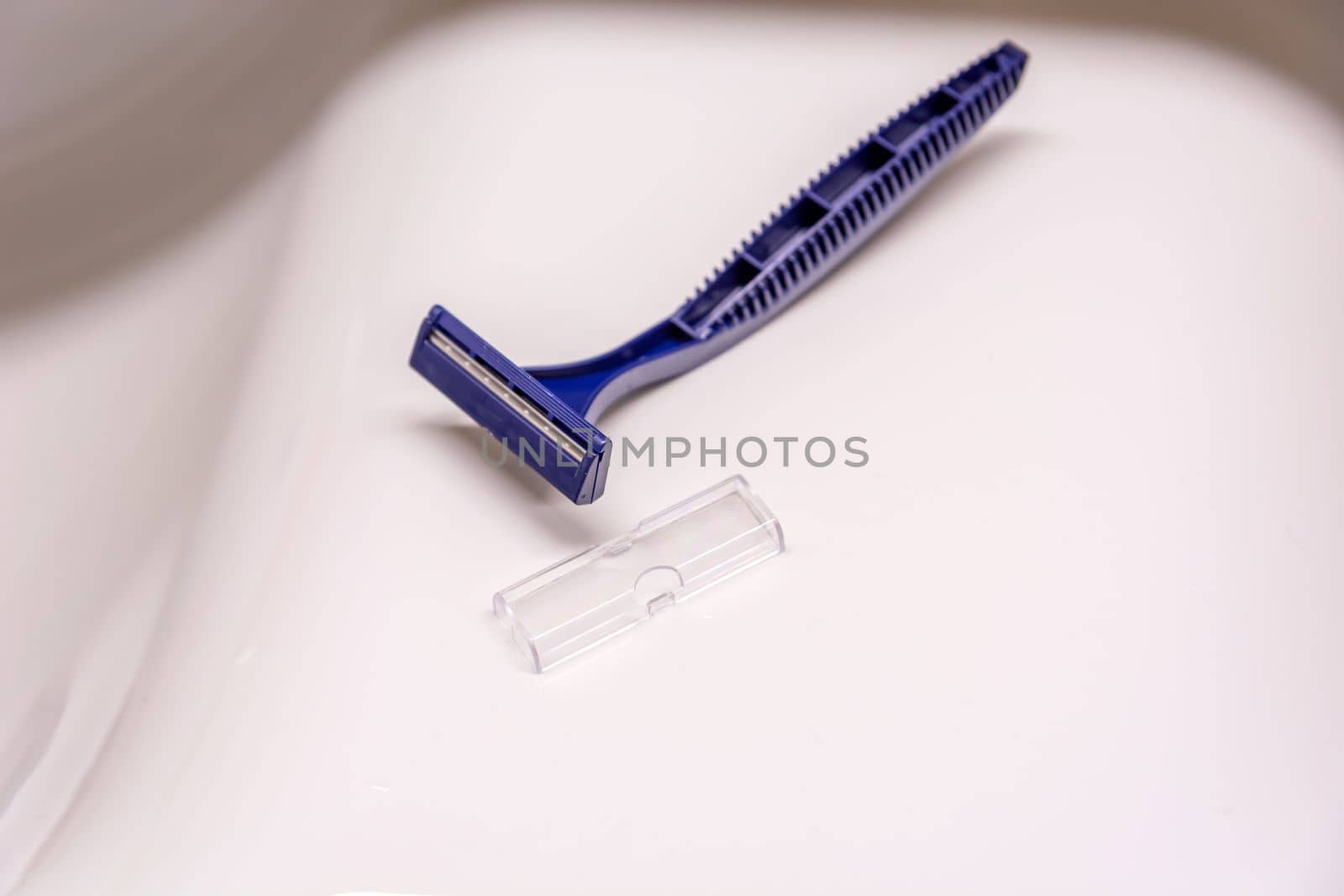 A disposable plastic blue razor lying on the sink
