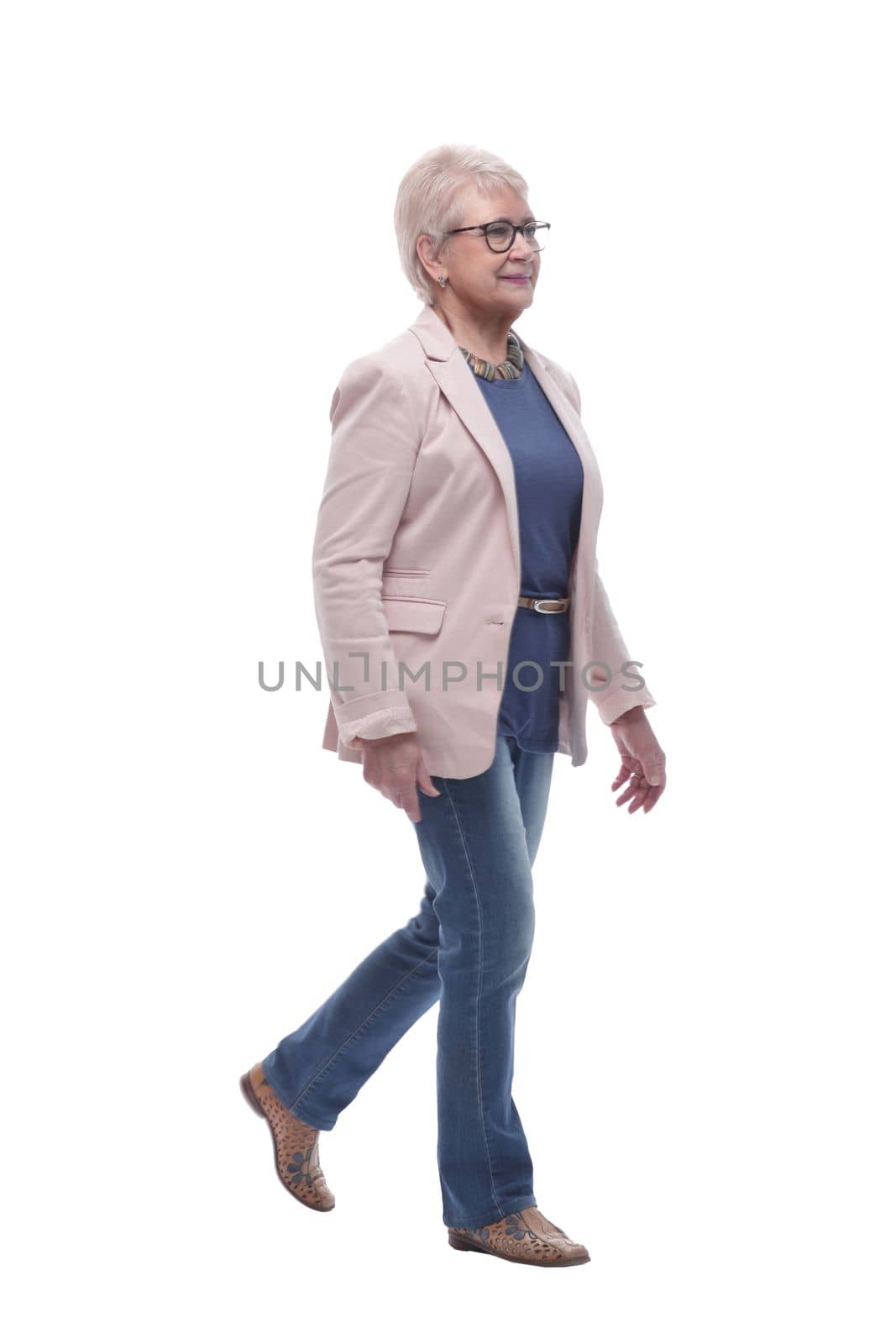 in full growth. confident senior woman goes forward . isolated on a white background