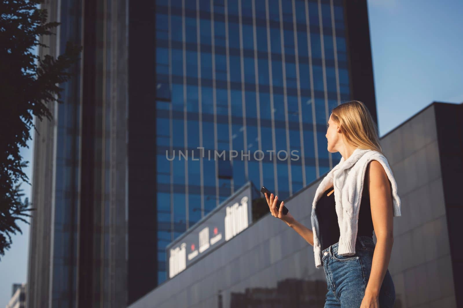 Young blonde woman in an urban setting using a mobile device by VisualProductions