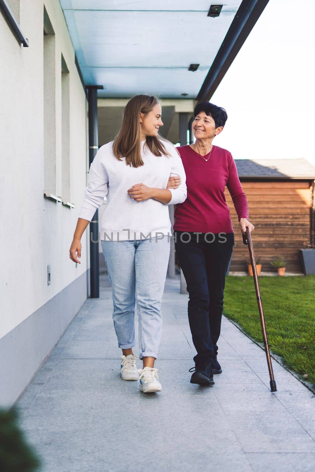 Vertical portrait of a nurse and senior woman holding hand in hand, nurse giving support to the elderly lady while she walks by VisualProductions