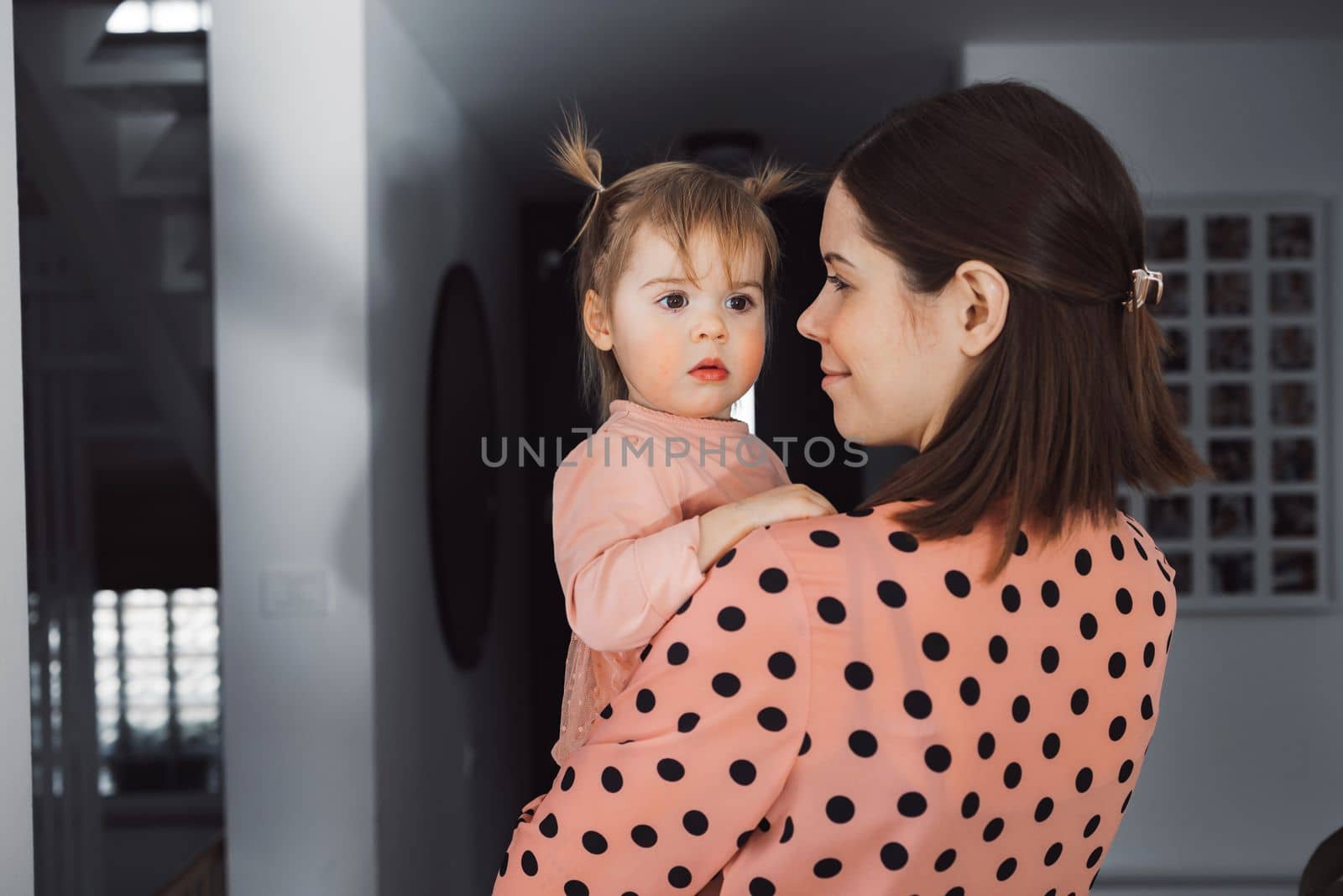 Waist up portrait young caucasian mom with baby girl in her arms by VisualProductions