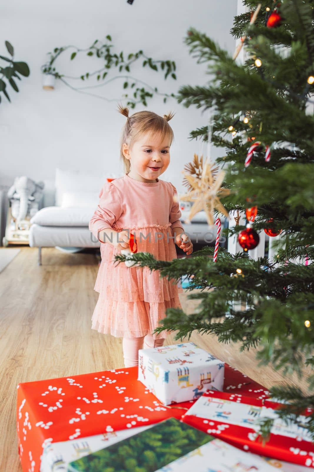 Vertical photo of excited little girl looking at all the Christmas presents underneath the Christmas tree by VisualProductions