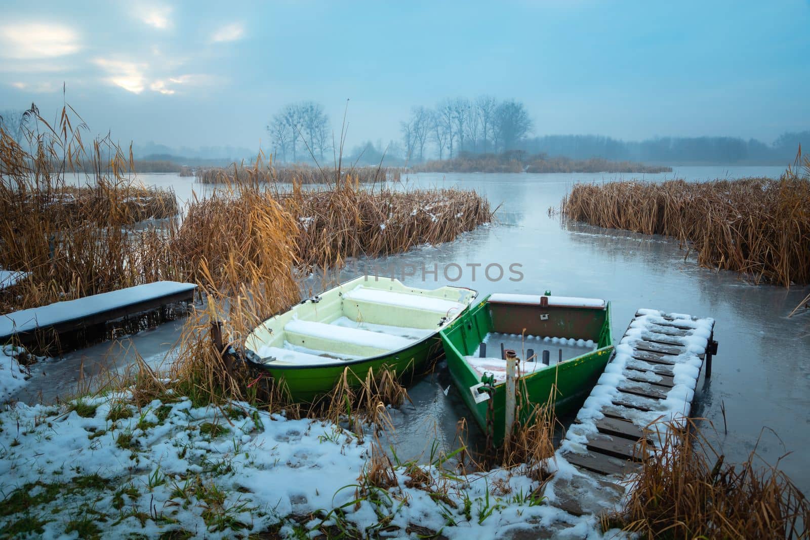 Small boats on the shore of a frozen lake