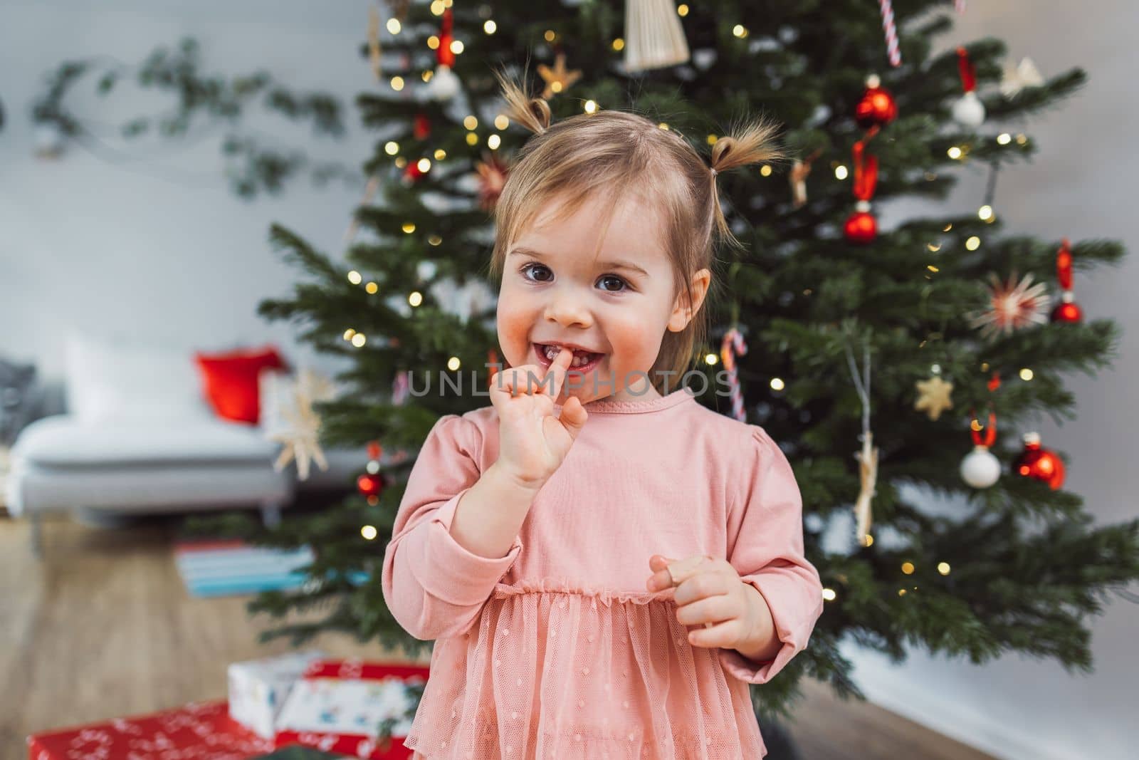 Young smiling caucasian baby girl portrait in front of the Christmas tree by VisualProductions