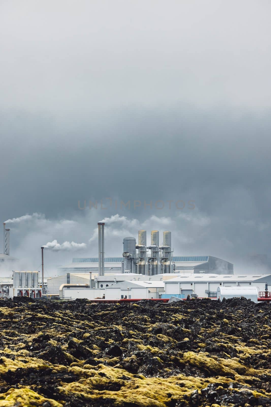 Geothermal Power Plant, hot water power station in Iceland. Steam rolling out of the plant chimneys, red large tubes running across the grounds filled with hot water. Sustainable, energy efficient Cloudy cold autumn day in Iceland.