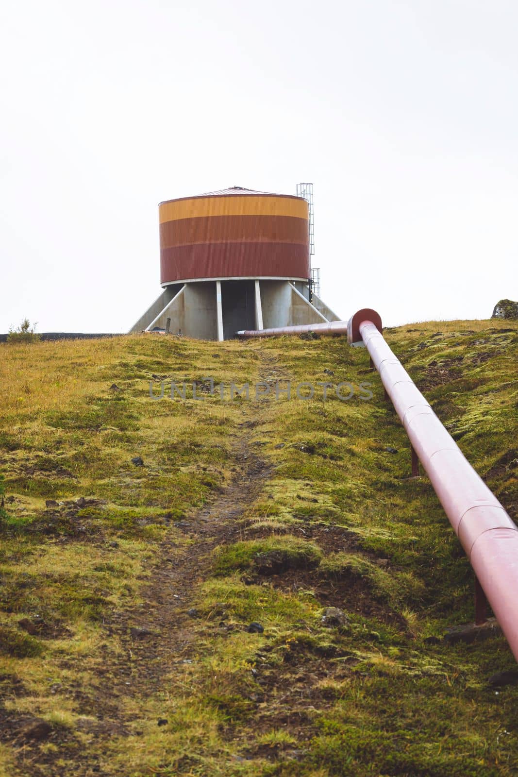 Geothermal Power Plant, hot water power station in Iceland. Steam rolling out of the plant chimneys, red large tubes running across the grounds filled with hot water. Sustainable, energy efficient Cloudy cold autumn day in Iceland.