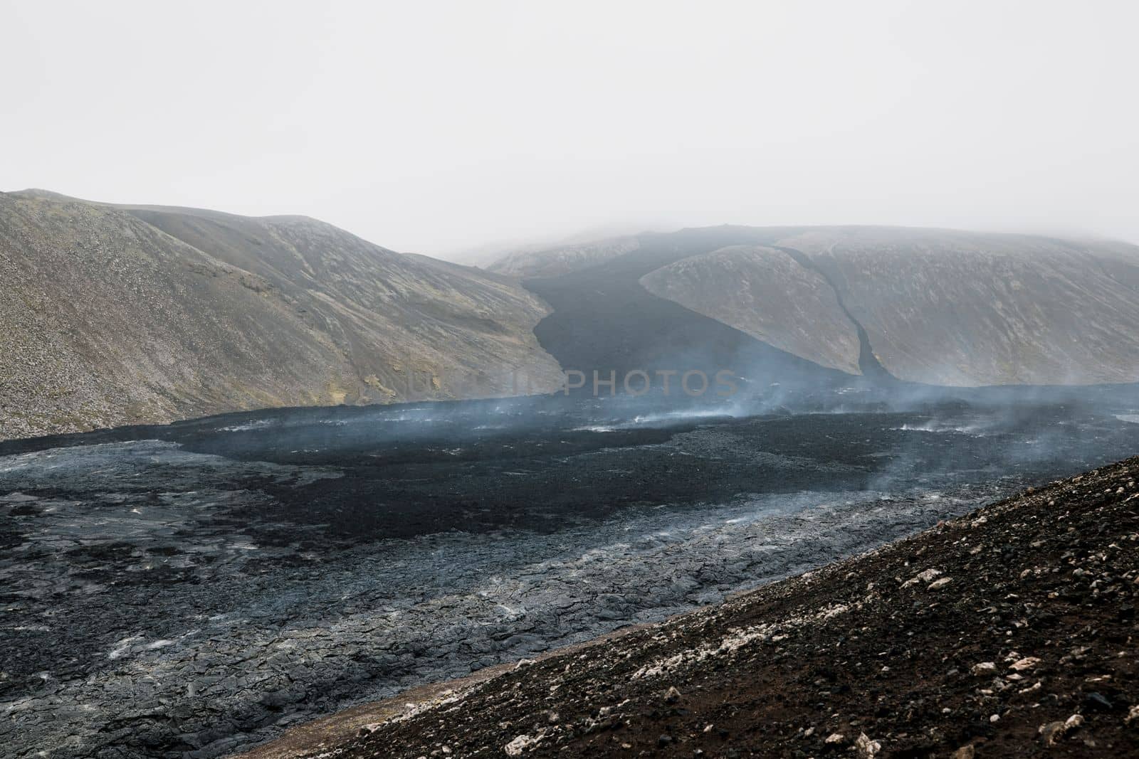 Geldingadalir active Volcano, errupting in 2021 - Fagradalsfjall and 2022 -Meradalir. Still hot lava rocks, steam comping up from the grounds. Dark grey, black volcanic rocks in Iceland. Dramatic view of lava rocks cold cloudy autumn day in Iceland.