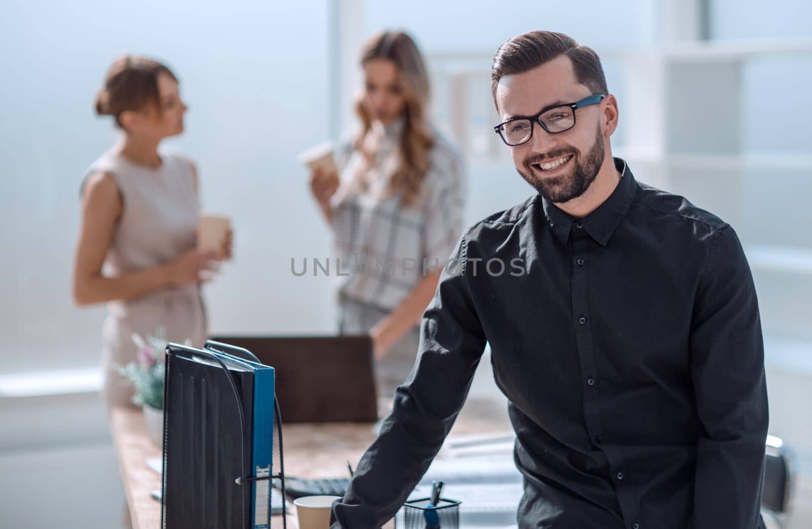 smiling young businessman standing in office. business concept