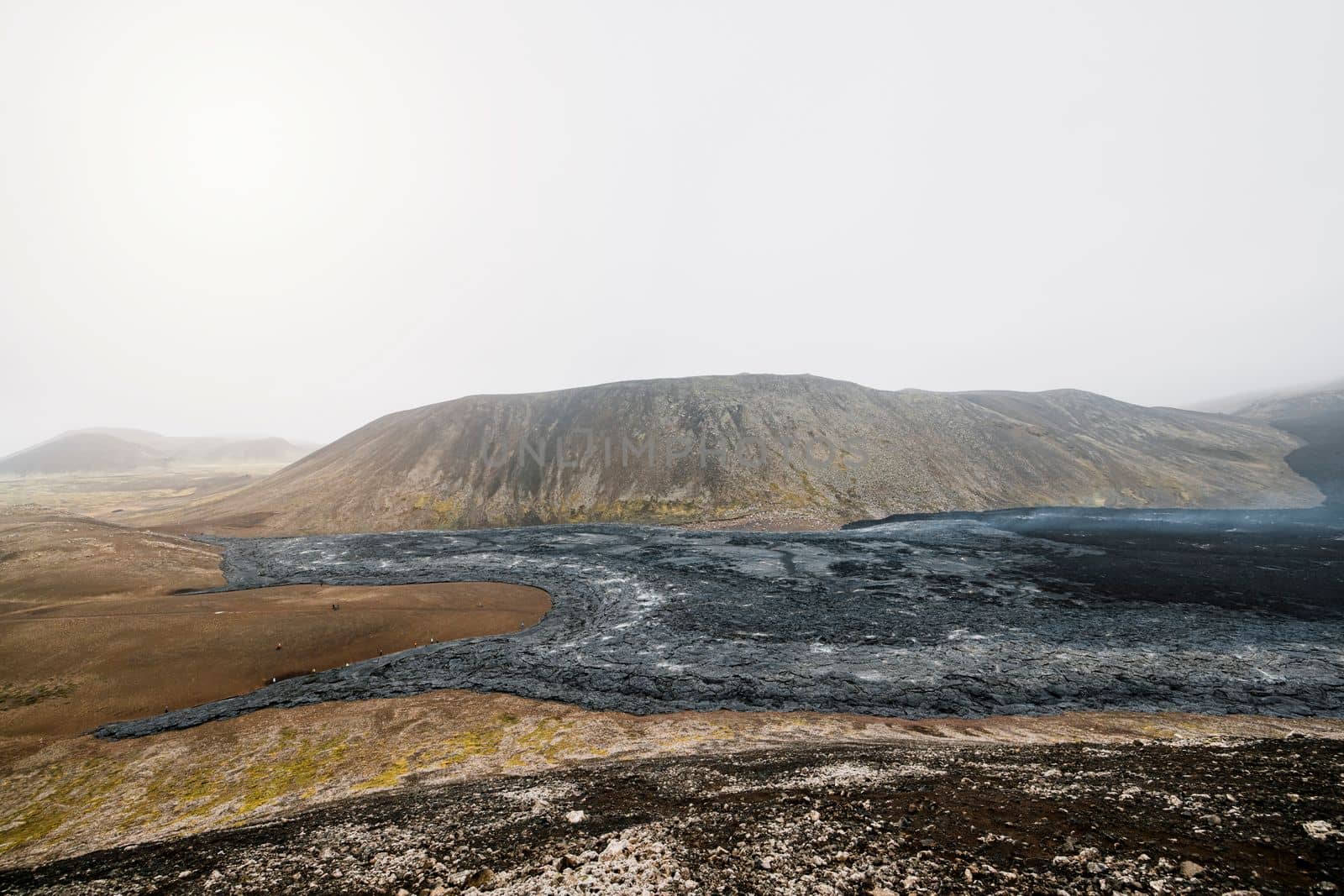 Geldingadalir active Volcano, errupting in 2021 - Fagradalsfjall and 2022 -Meradalir. Still hot lava rocks, steam comping up from the grounds. Dark grey, black volcanic rocks in Iceland. Dramatic view of lava rocks cold cloudy autumn day in Iceland.