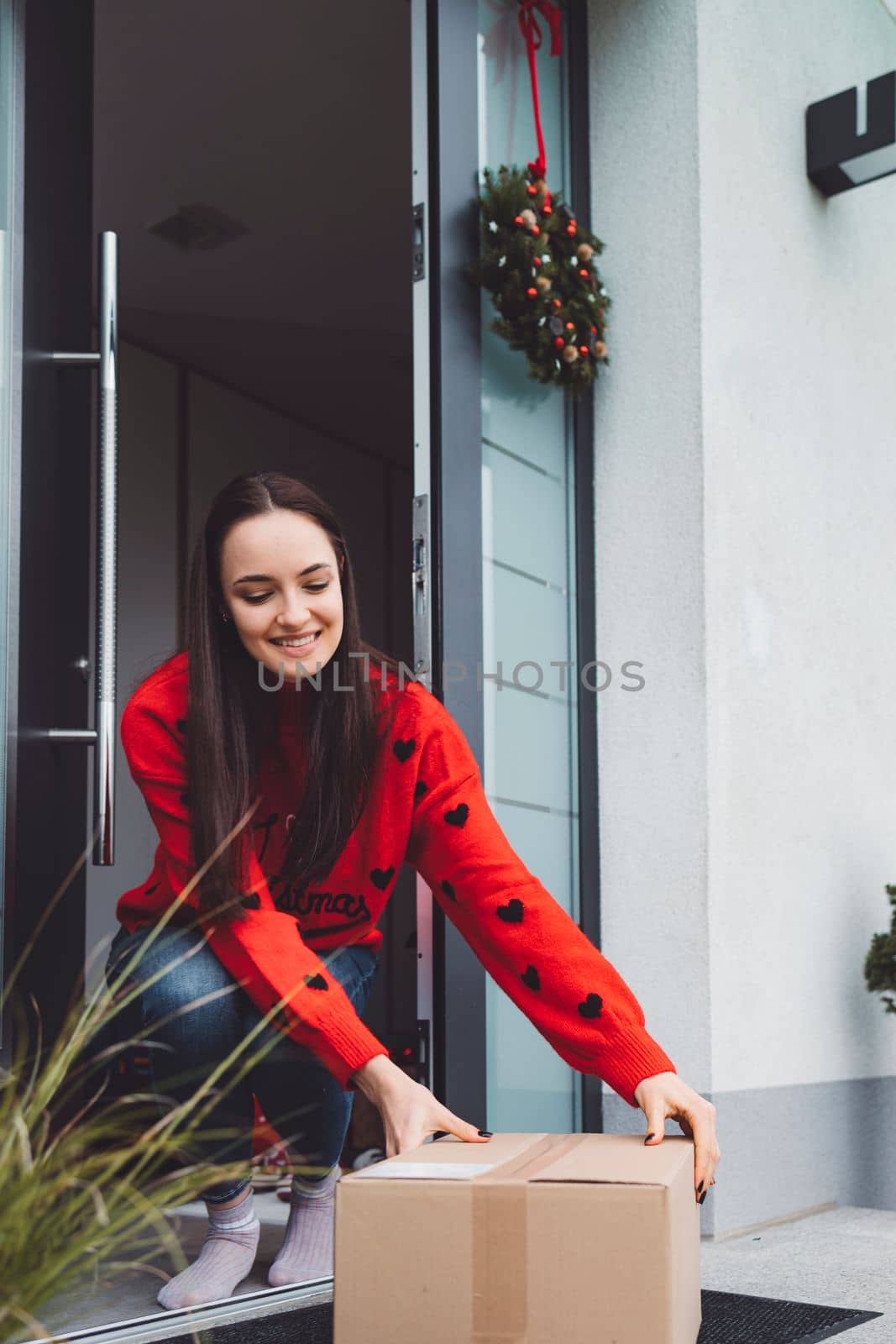 Cheerful young woman excited over a package she just received. Woman getting her christmas gift in the mail. Opening the Christmas present at home.