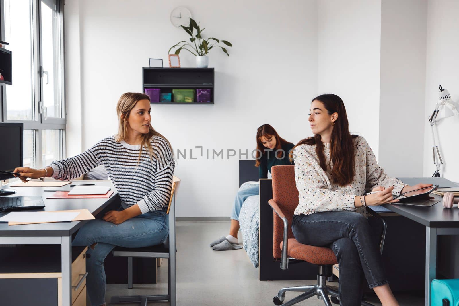 Group of three friends, roommates, studying in the dorm room together by VisualProductions