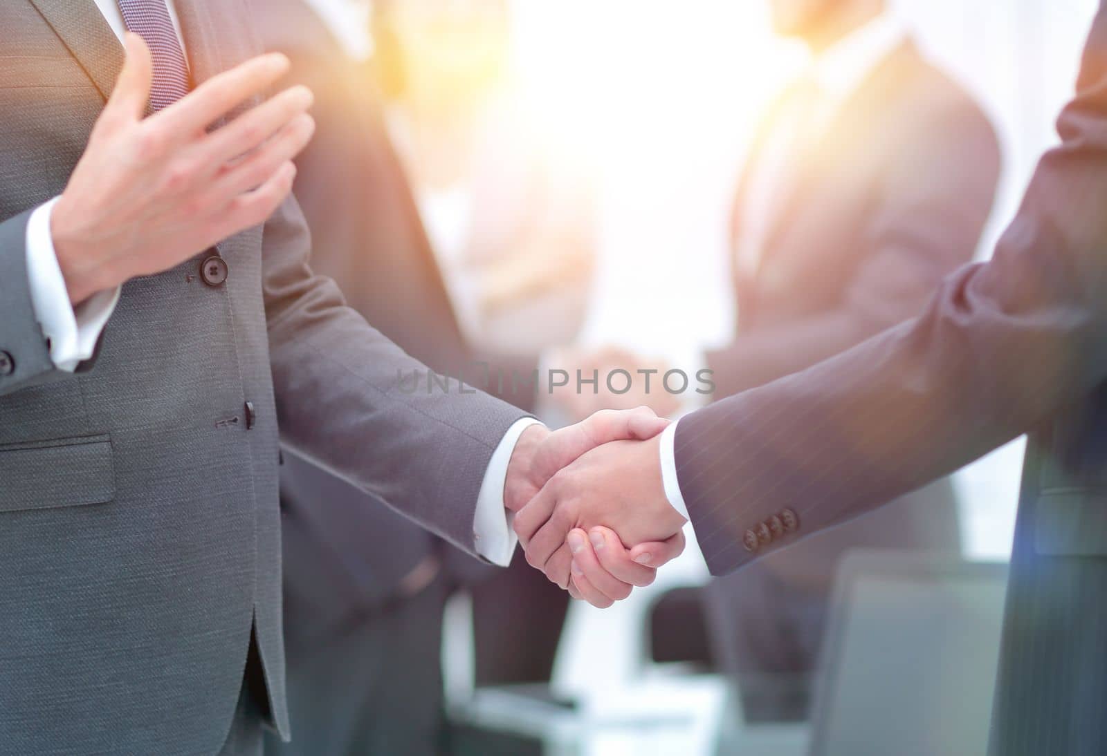 Business partners handshaking over business objects on workplace by asdf