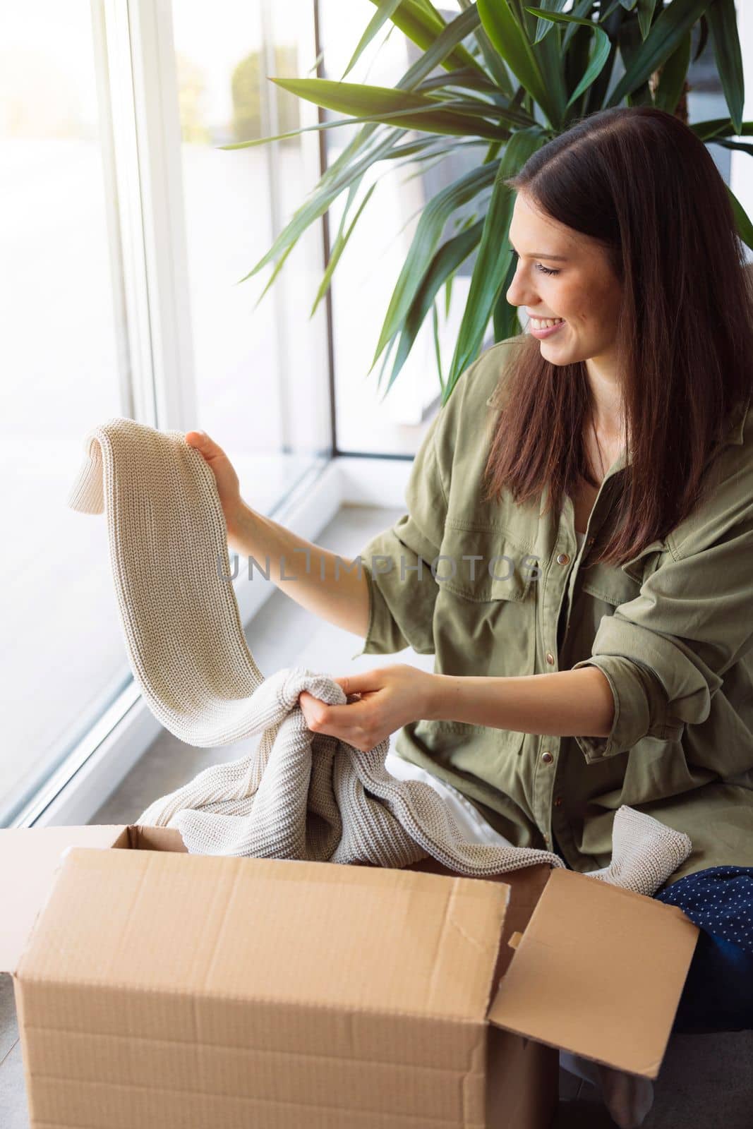 Woman excited to look trough her online order on winter clothes by VisualProductions