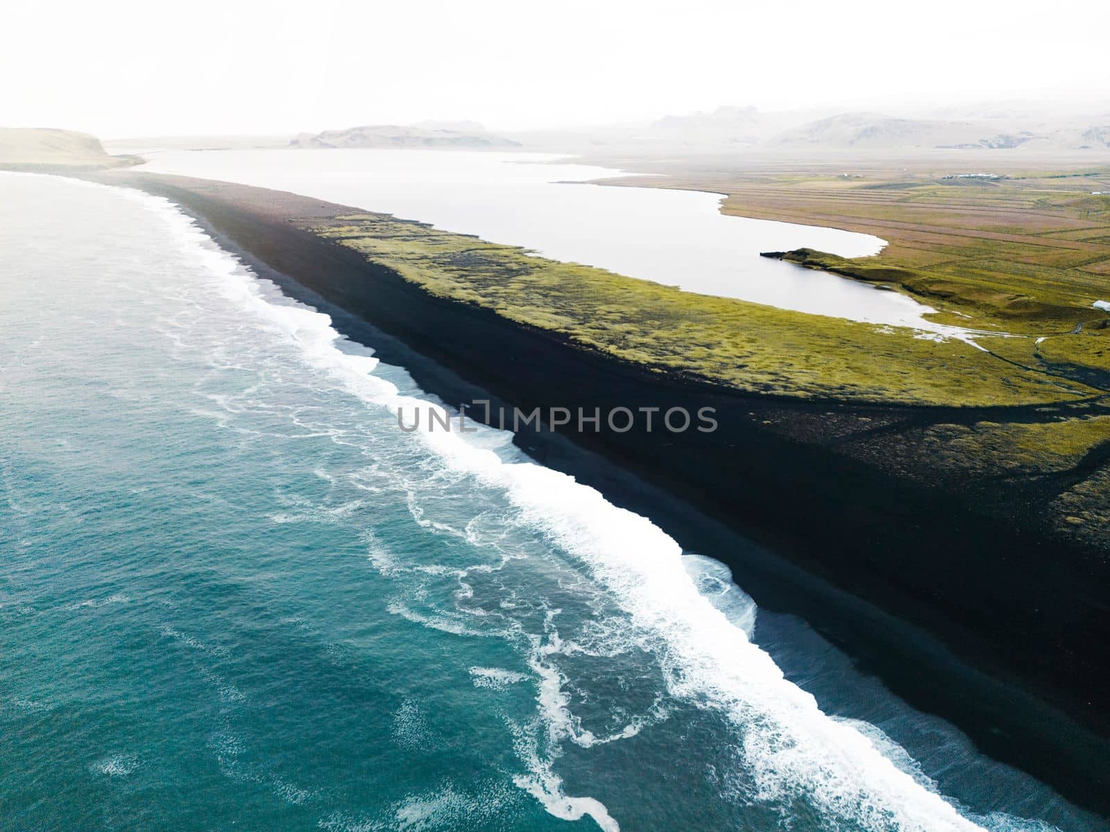 Volcanic Black Sand Beach with a view of Reynisdrangar. Waves crashing on the black sand beach. Vik, Iceland. High quality photo