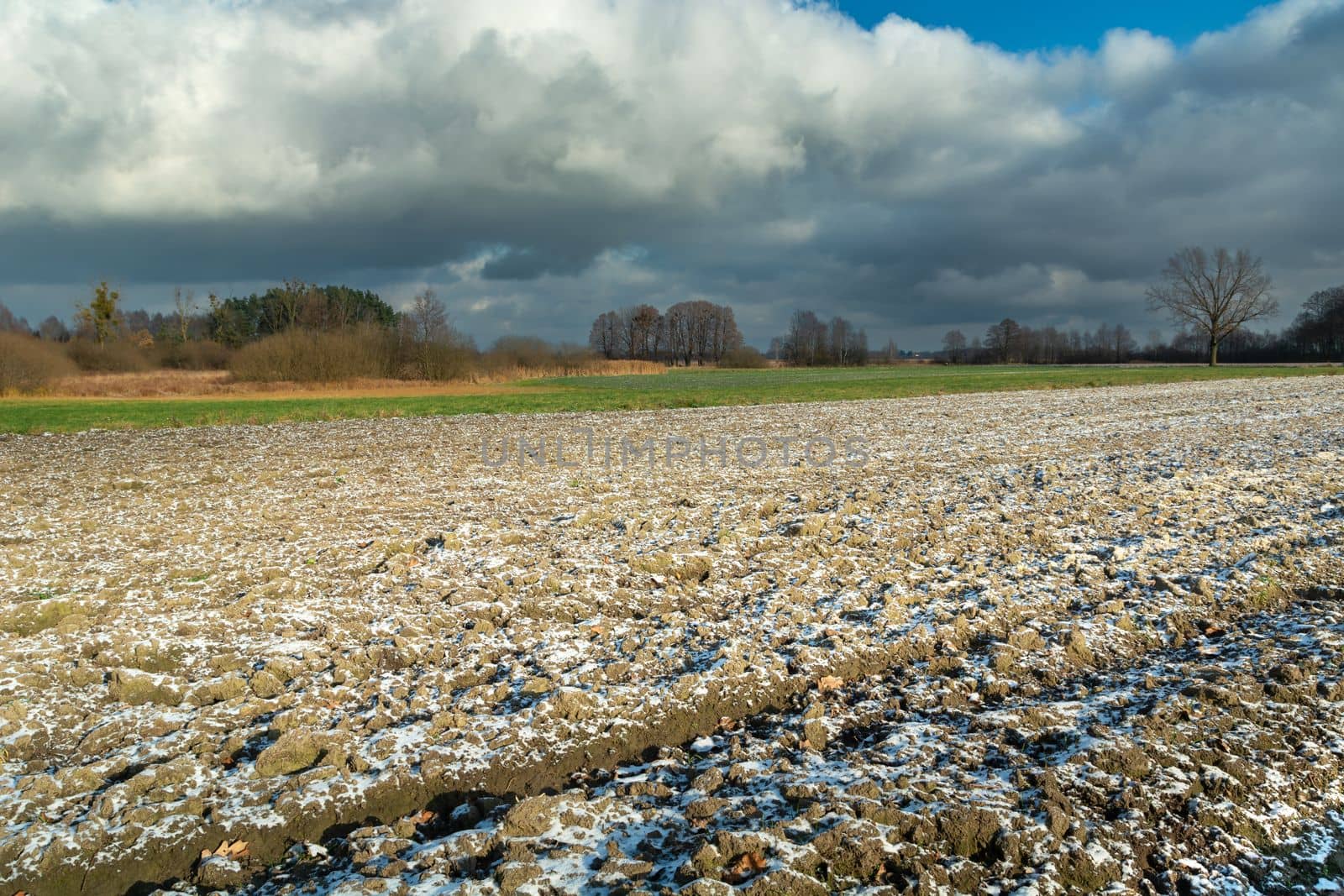 Small snow on a plowed field and cloudy sky, eastern Poland