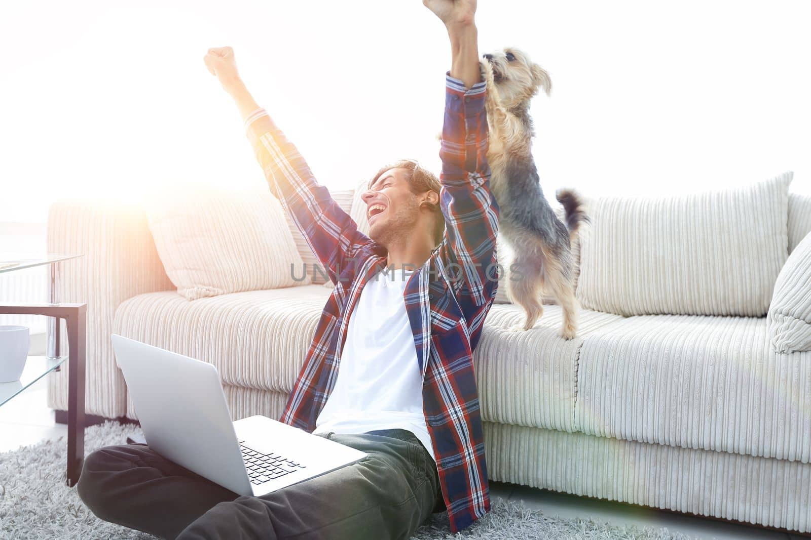 happy guy exults with his dog sitting near the sofa in the living room. by asdf